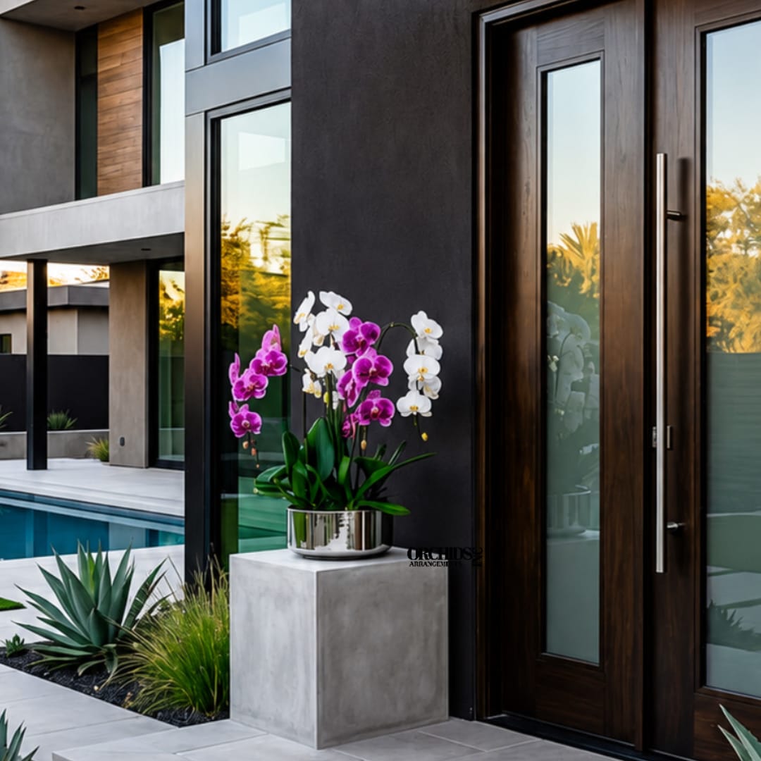 Purple and white orchids in a silver pot on a pedestal outside a modern house