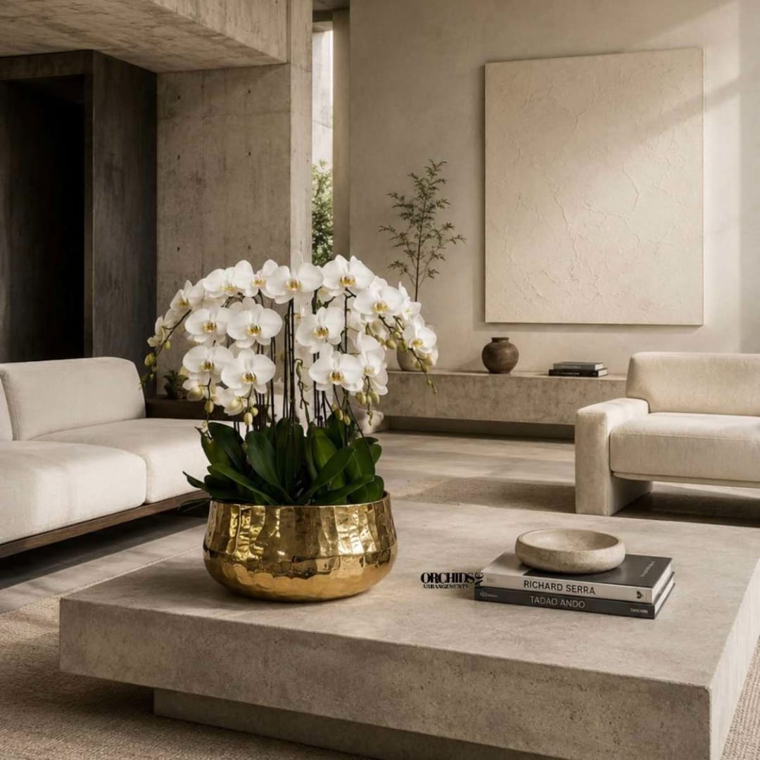 White orchids arranged in a gold bowl on a low table