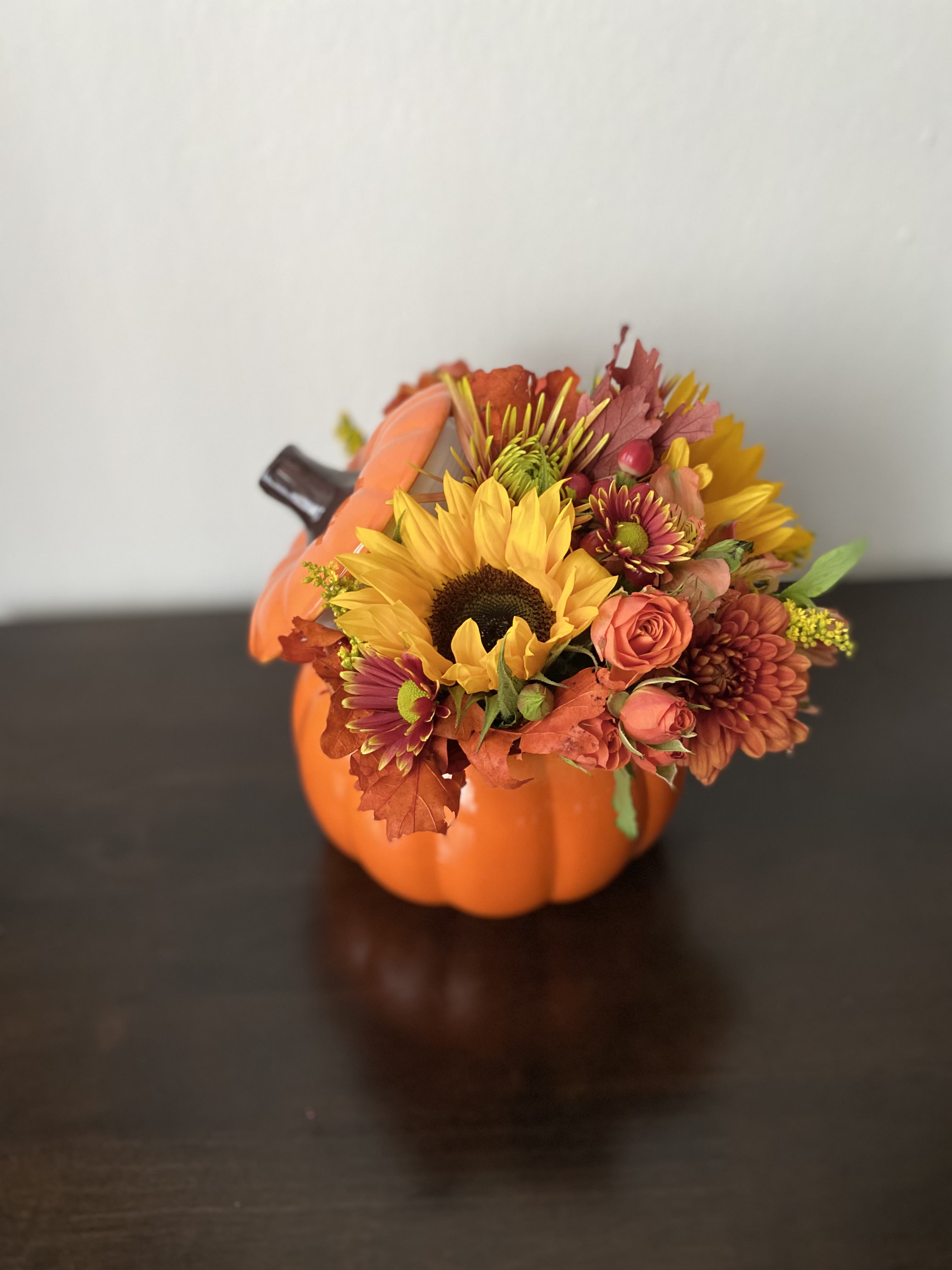 Large Ceramic festive pumping  - Approximately 11” wide, 10” tall   Festive pumpkin with spray roses moms, sunflowers, alstroemeria and fall leaves.  Delux and Premium version contains large roses. 