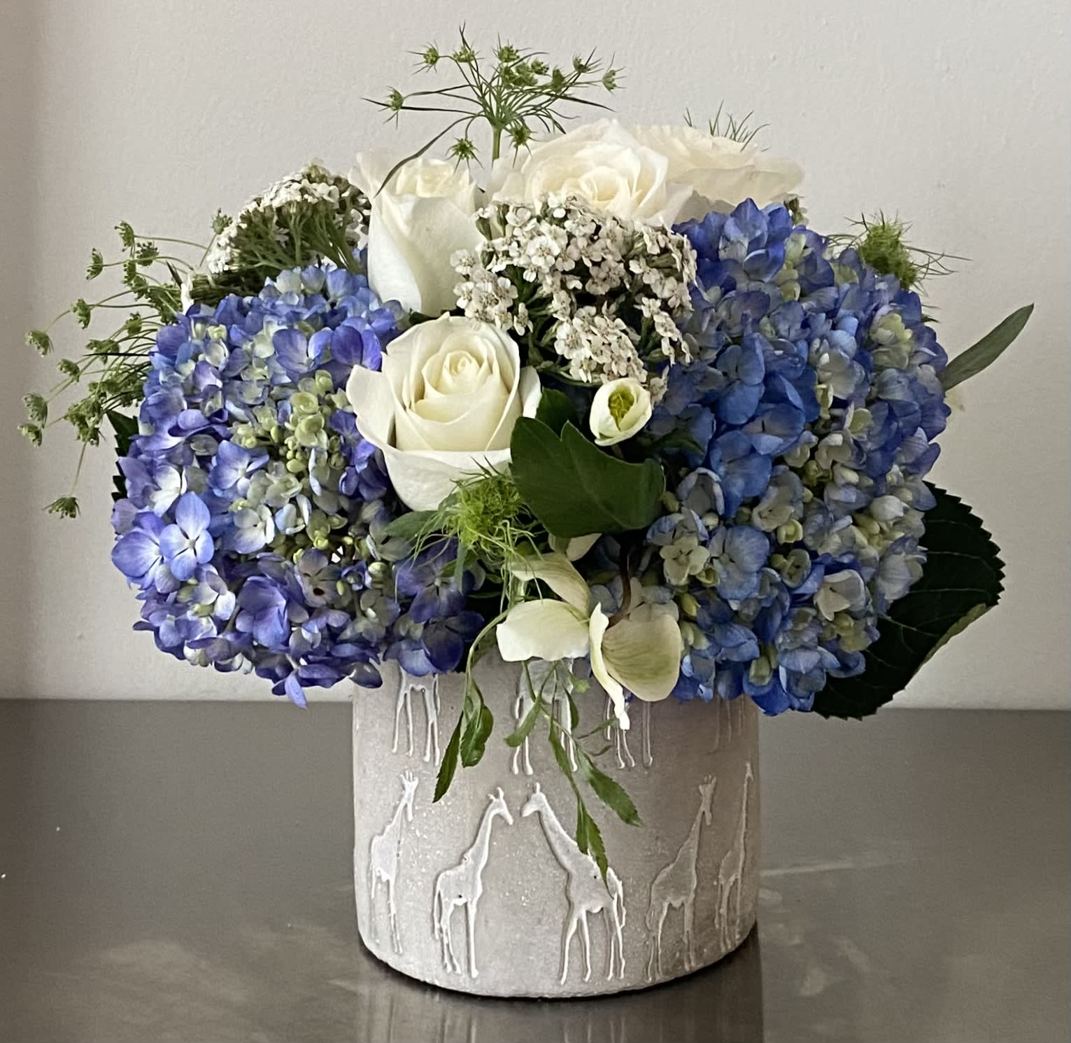 Blue hydrangeas and white roses arranged in a textured vase