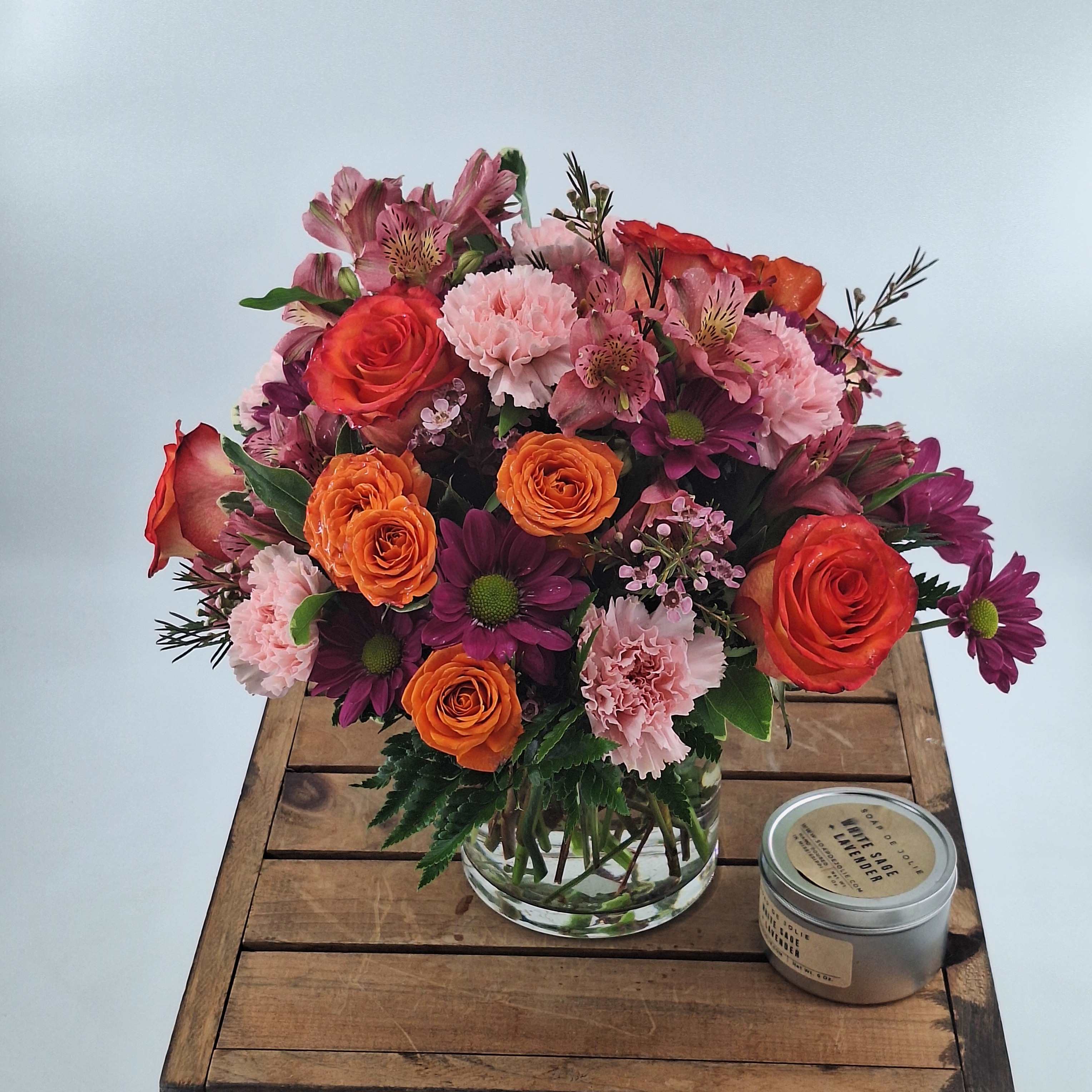 Mixed bouquet of pink, orange, and purple flowers in a clear glass vase