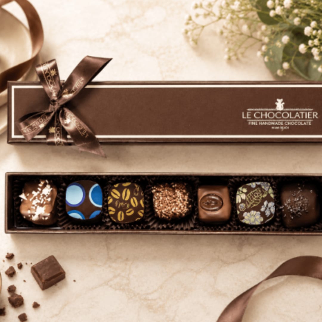 Box of assorted chocolates with a ribbon bow and open tray