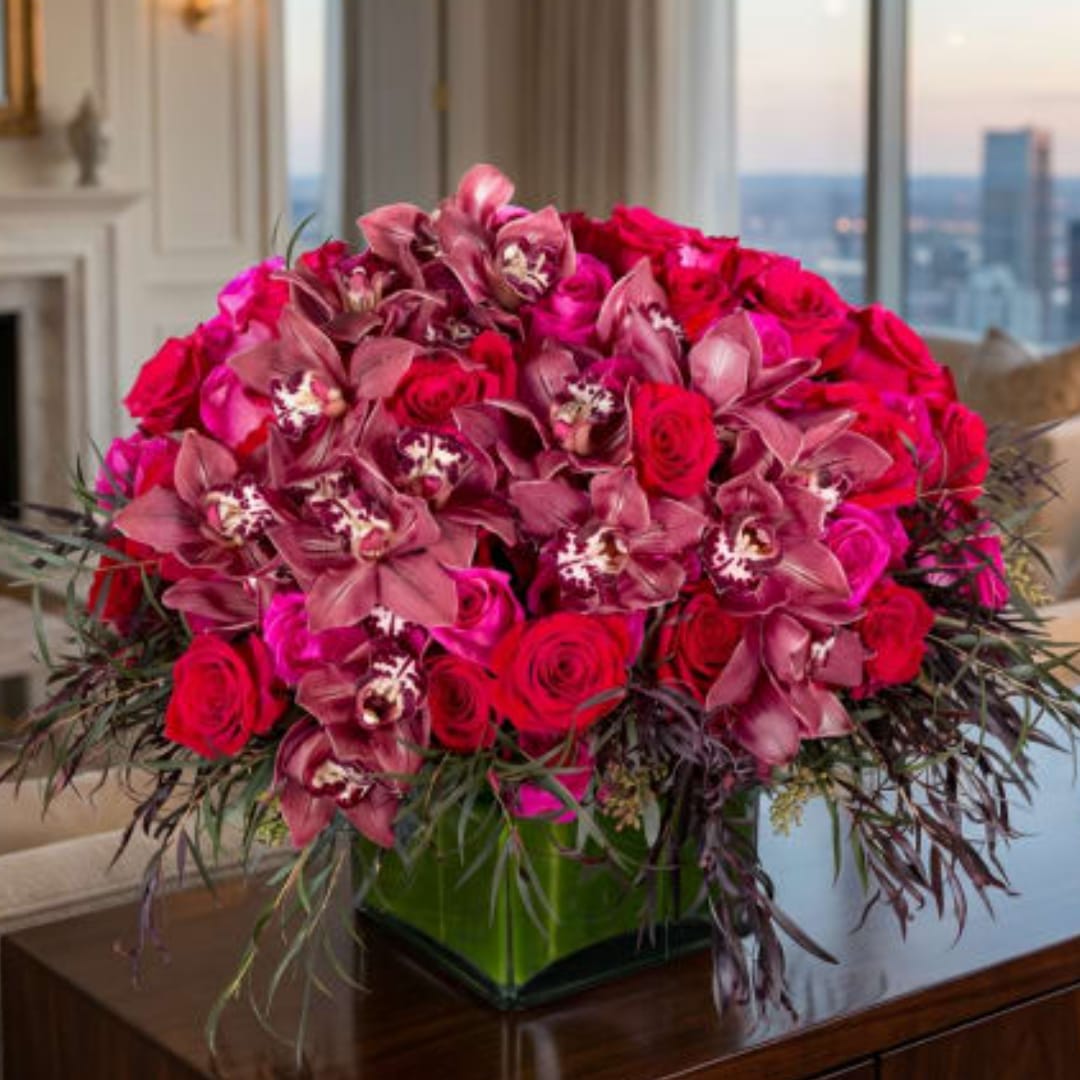 Pink roses and orchids arranged in a square glass vase