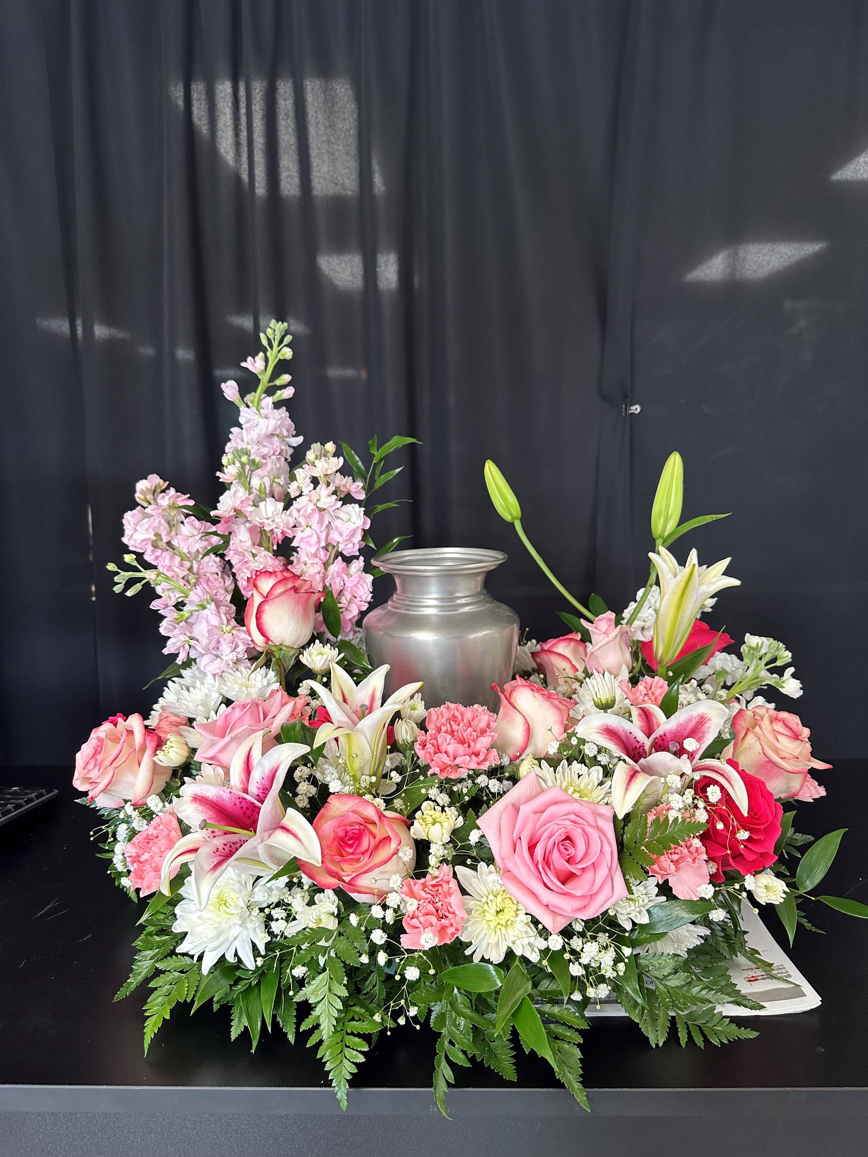 Pink and white floral arrangement around a silver urn
