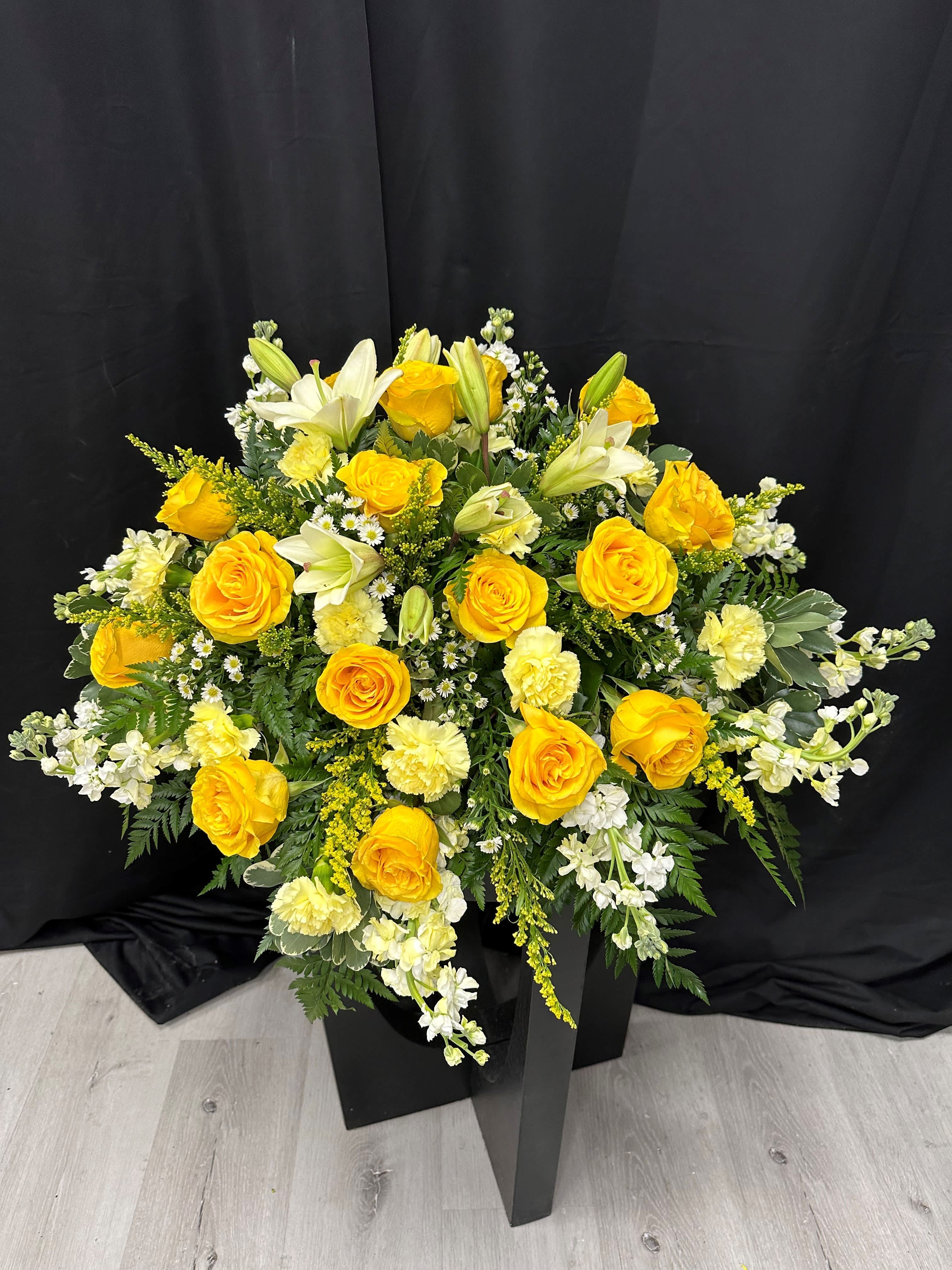 Yellow roses and white lilies in a black pedestal arrangement