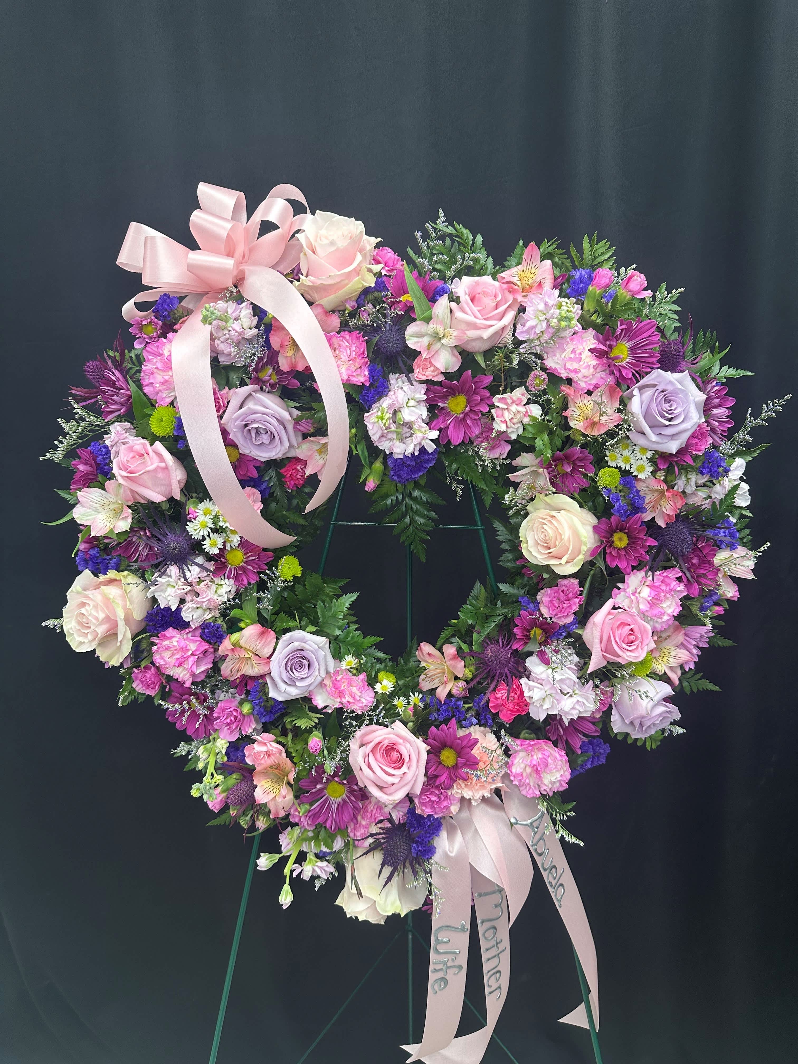 Heart-shaped floral wreath with pink and purple flowers and a ribbon bow