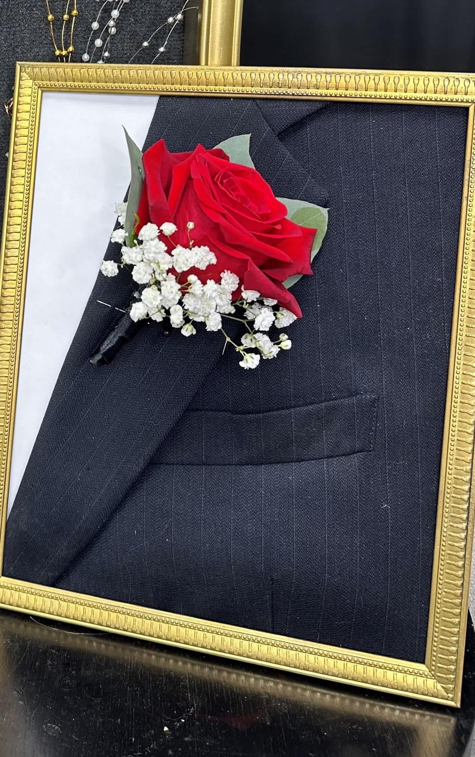 Red rose boutonniere with white baby's breath in a gold frame