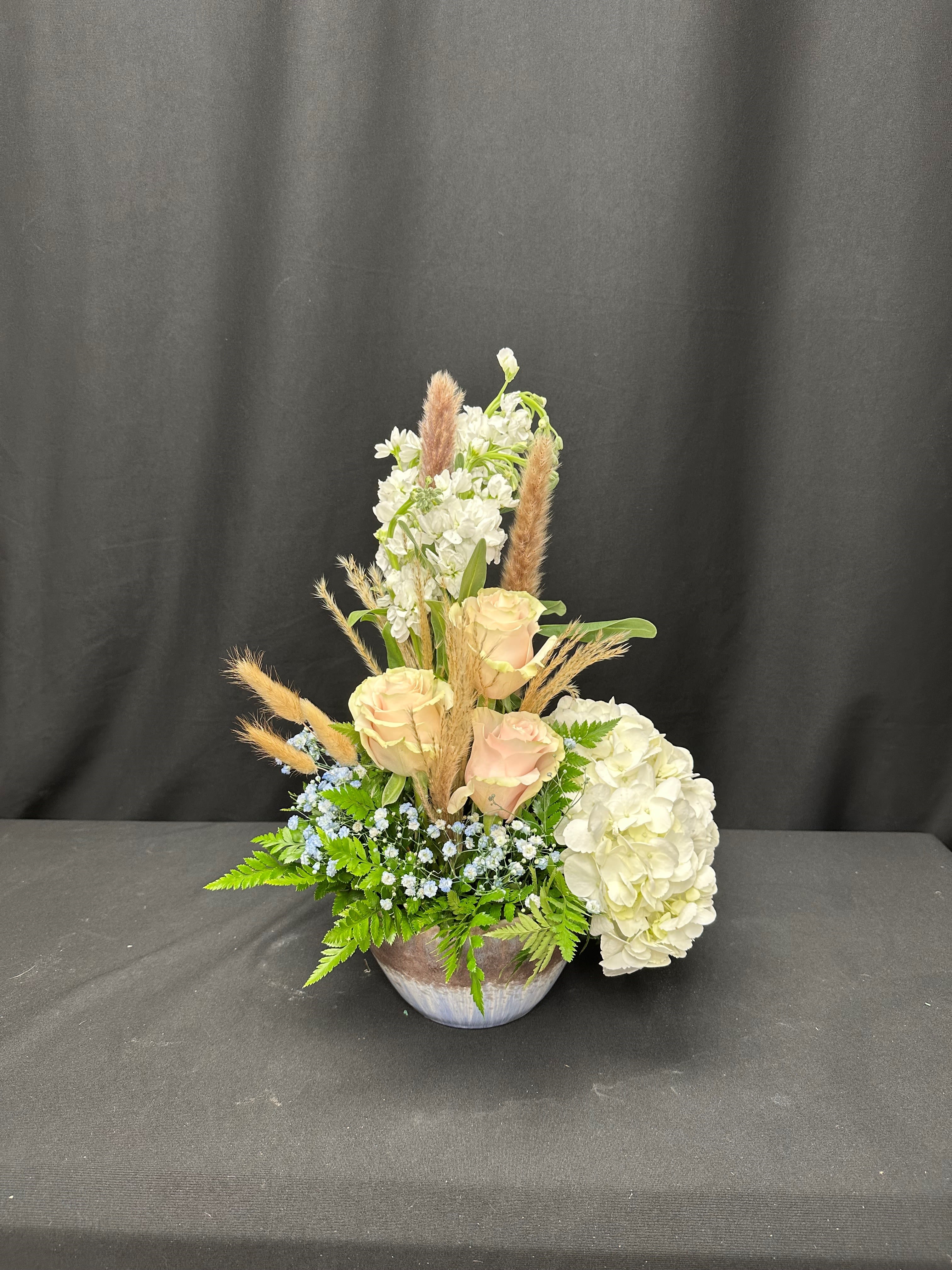 Cream roses and white hydrangeas in a low bowl arrangement