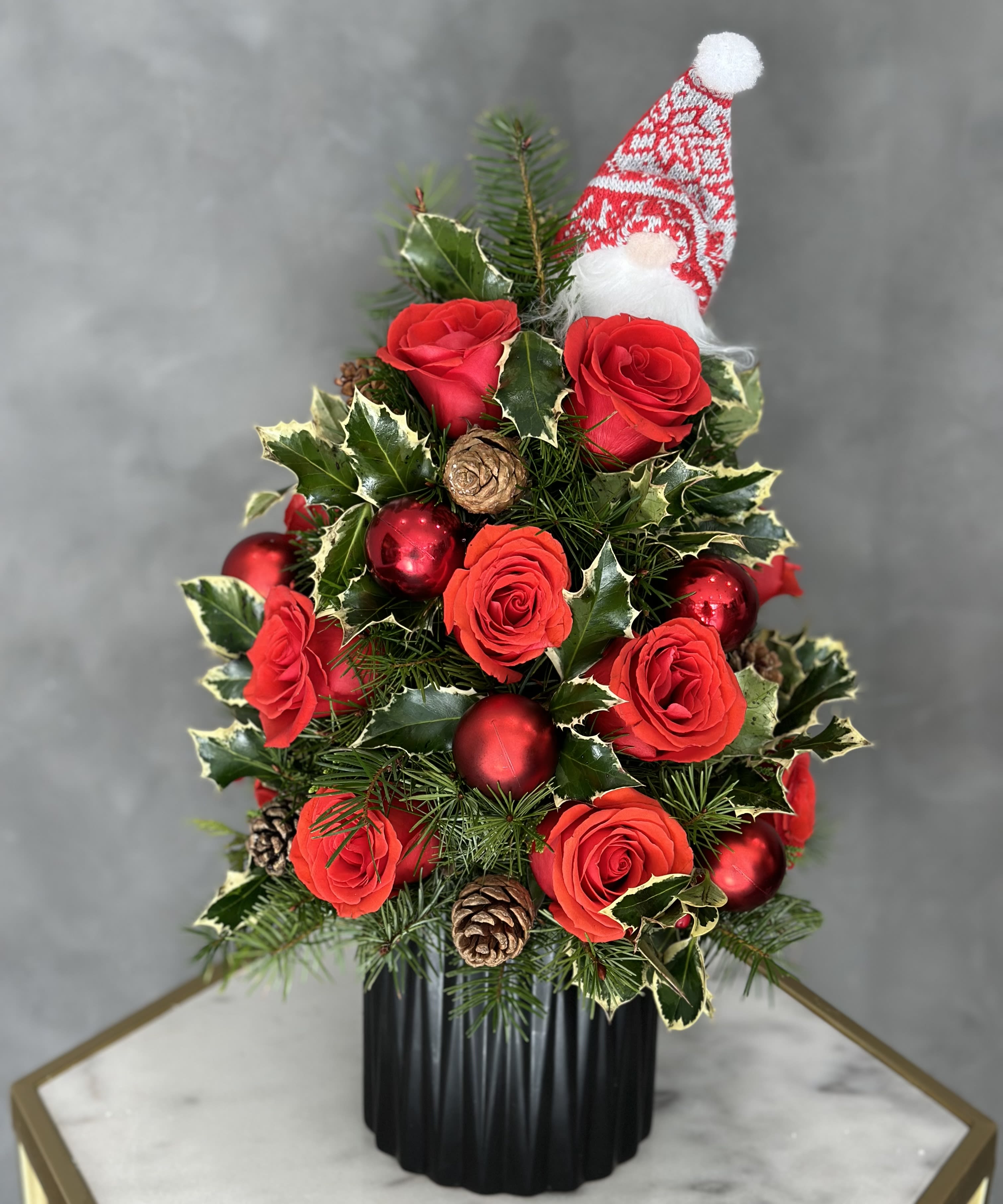 Christmas arrangement with red roses, ornaments, and a Santa hat