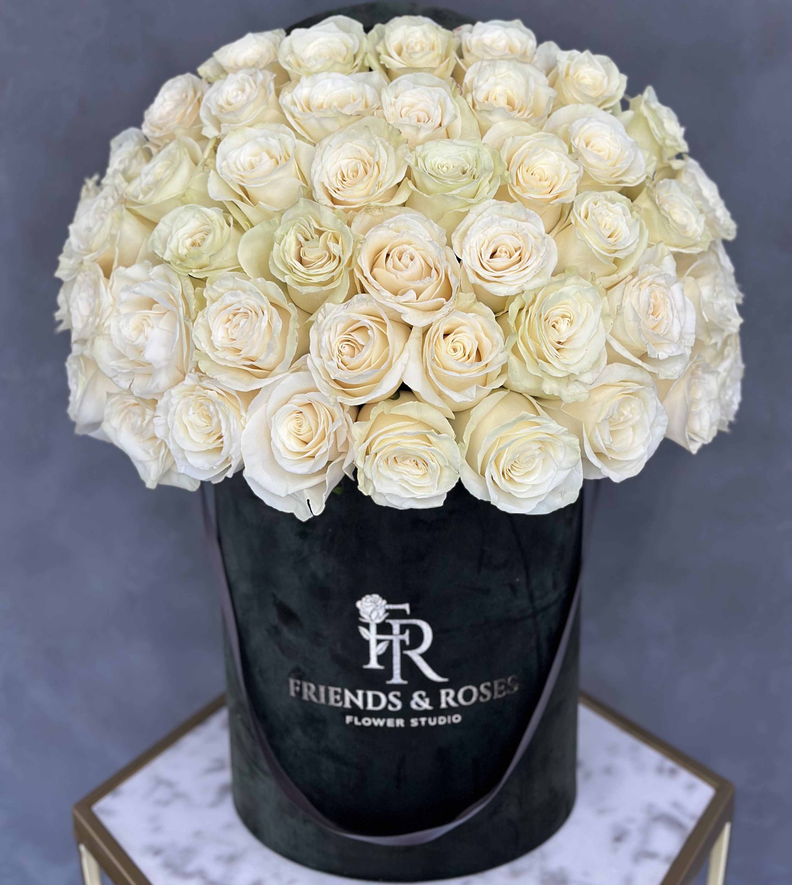 Cream-white roses arranged in a black hatbox