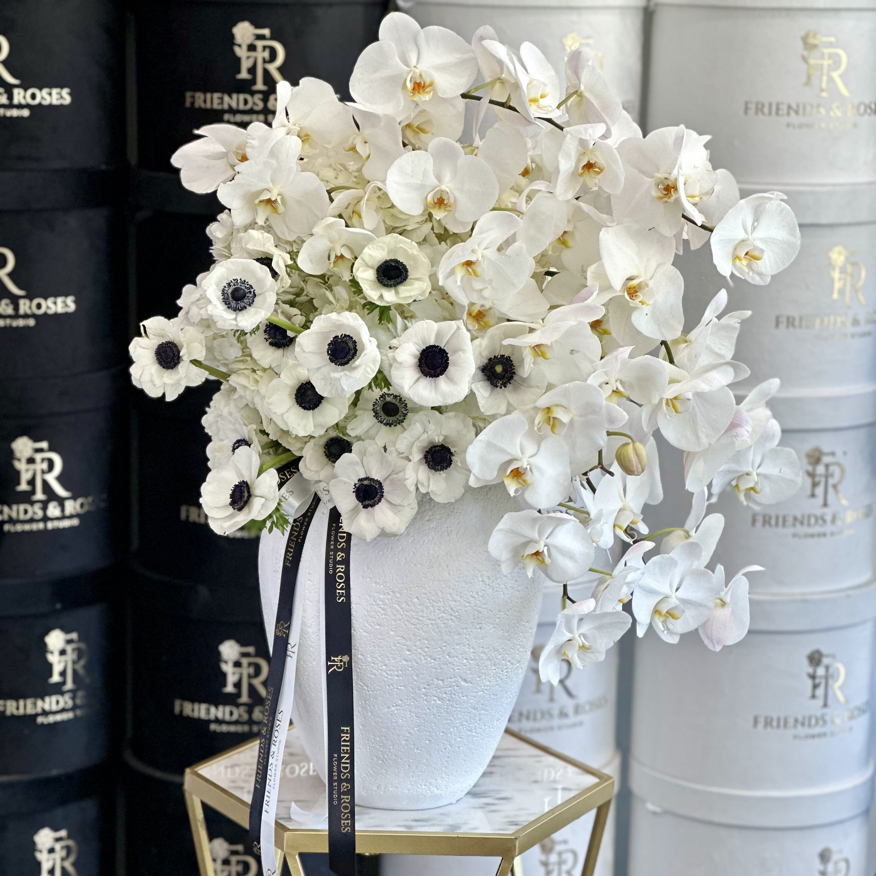 White orchids and anemones arranged in a white vase
