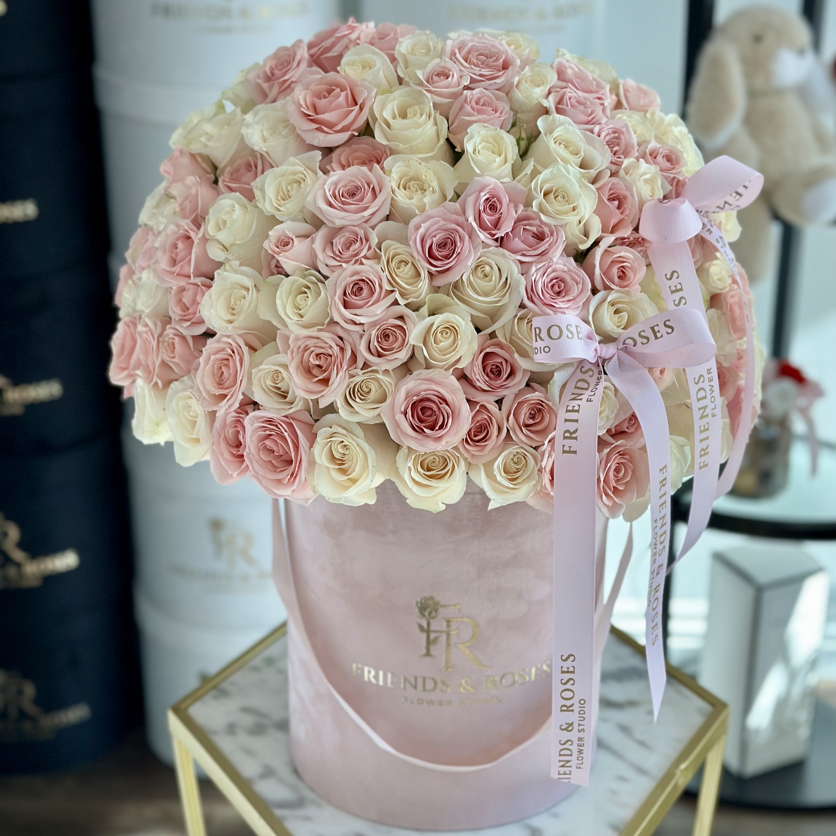 Large bouquet of pink and cream roses in a pink hatbox with ribbon