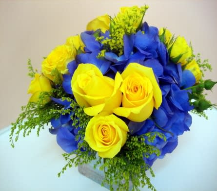 Yellow roses and blue hydrangeas arranged in a compact bouquet