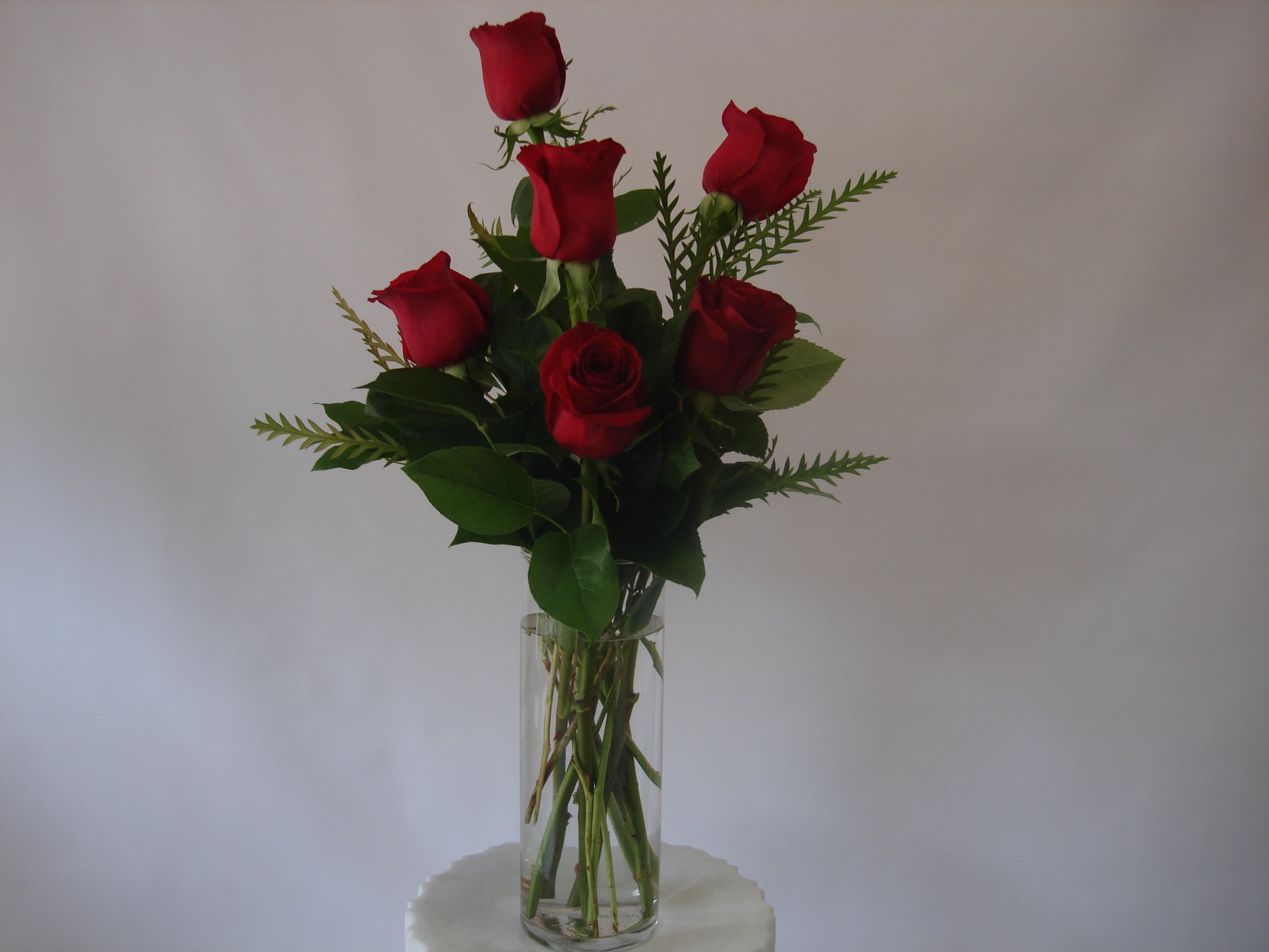 Six red roses in a clear glass vase