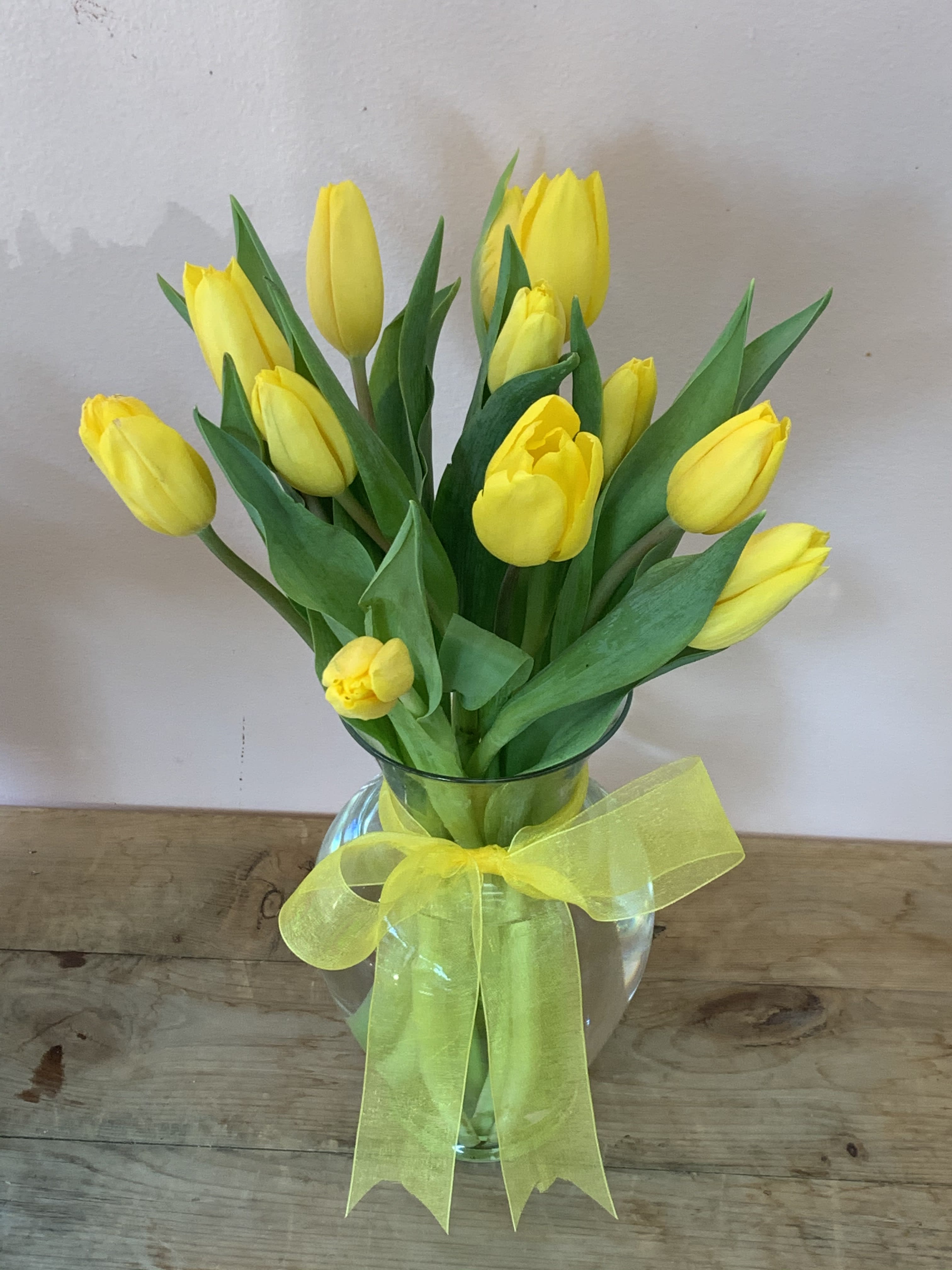 10  Yellow Tulips - W803 - Sunny yellow tulips are a sure sign of spring. Even if the weather is not cooperating you can be sure the person who receives this bright bouquet will feel the warmth of your message. Dazzling yellow tulips are delivered in an exclusive glass vase that's all wrapped up with…what else…a bright yellow ribbon. So go ahead and send sunshine. Even (or especially) if it's a cloudy day!Approximately 12 1/2" W x 14 3/4" H Orientation: All-Around As Shown : W803