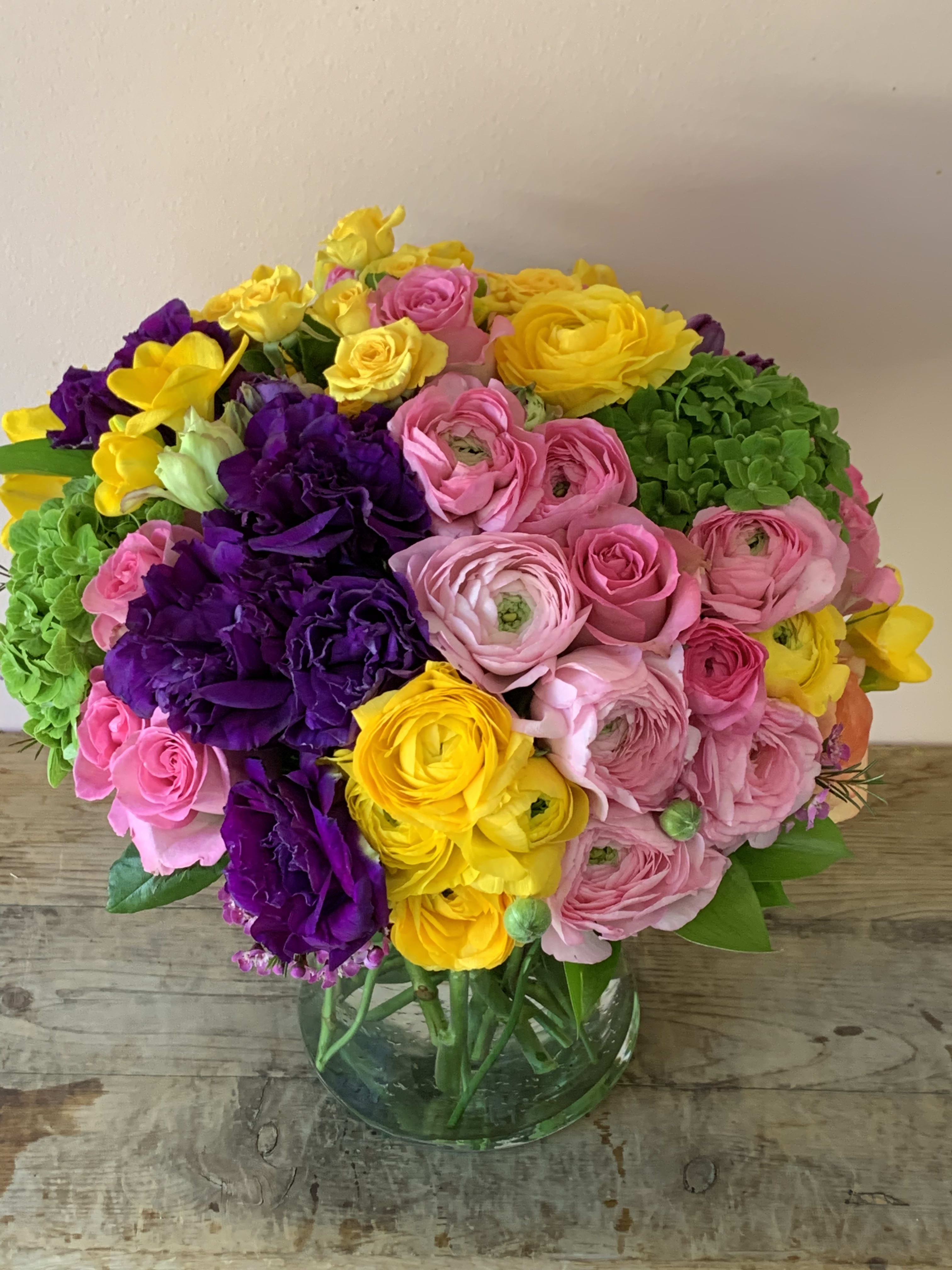Bright bouquet of pink, yellow, and purple flowers in a glass vase