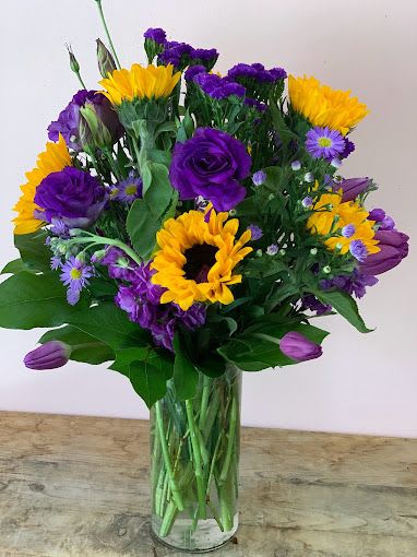 Bouquet of purple and yellow flowers in a clear glass vase