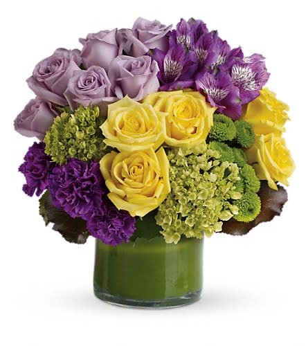 Bouquet of lavender, yellow, and purple flowers in a green glass vase