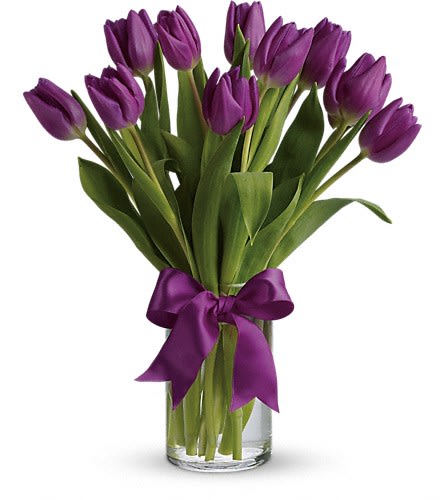 Purple tulips in a clear glass vase tied with a purple ribbon