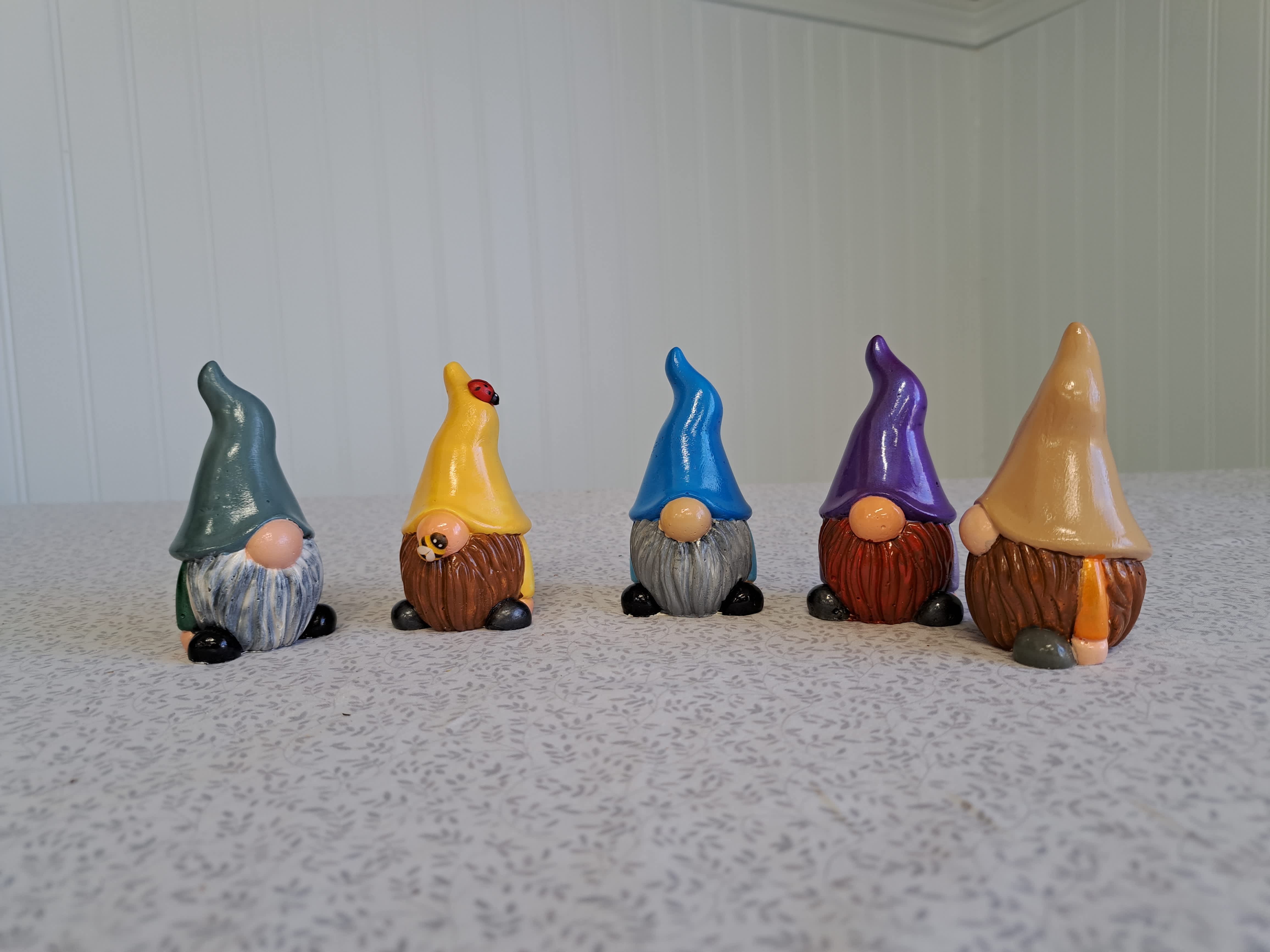 Five small painted gnome figurines lined up on a tabletop