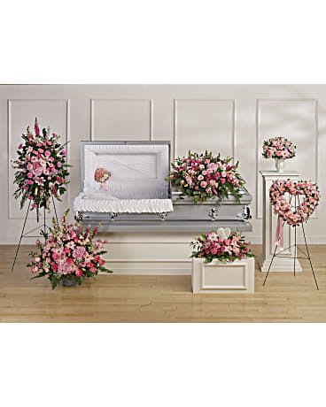 Funeral casket surrounded by pink floral sprays and wreaths