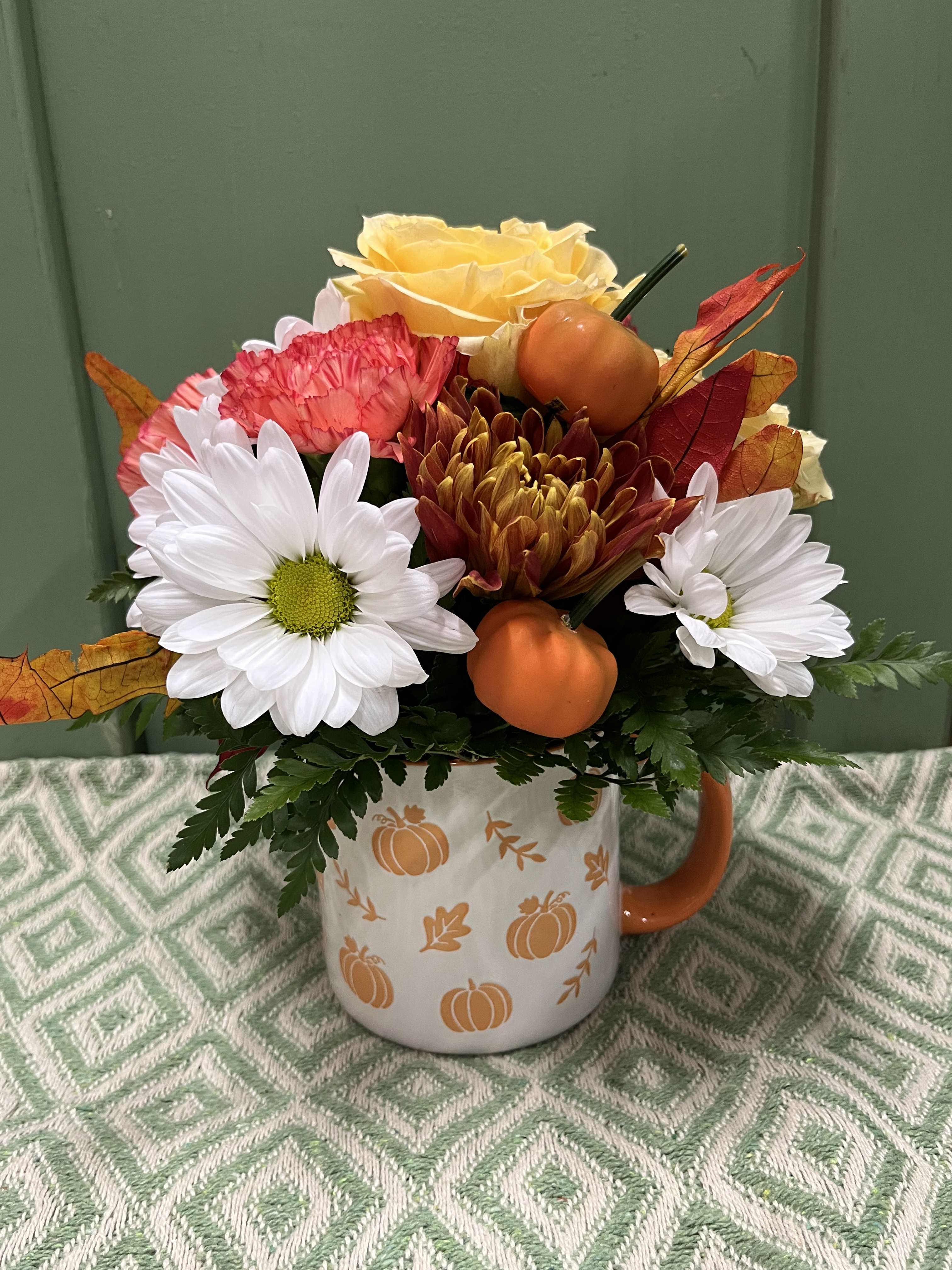 Fall flower arrangement in a pumpkin-decorated mug with daisies and roses