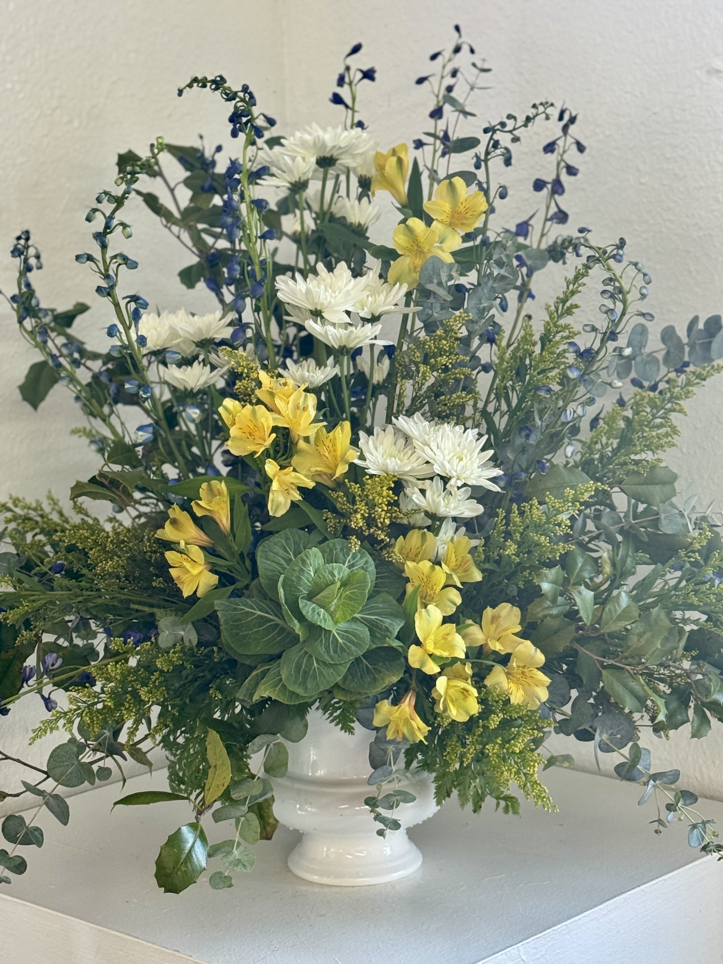 White and yellow flowers in a white pedestal vase