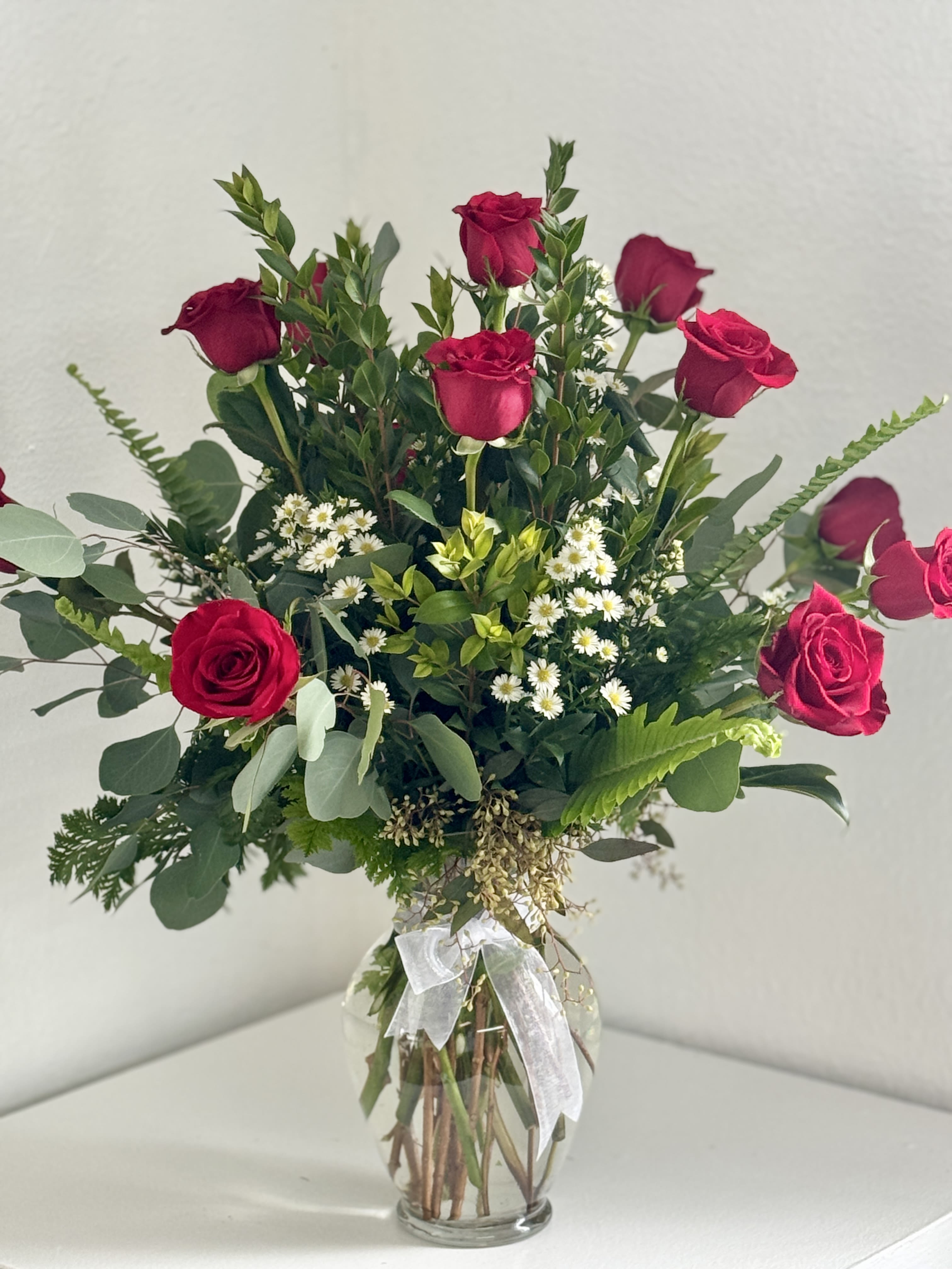 Bouquet of red roses and small white flowers in a clear glass vase