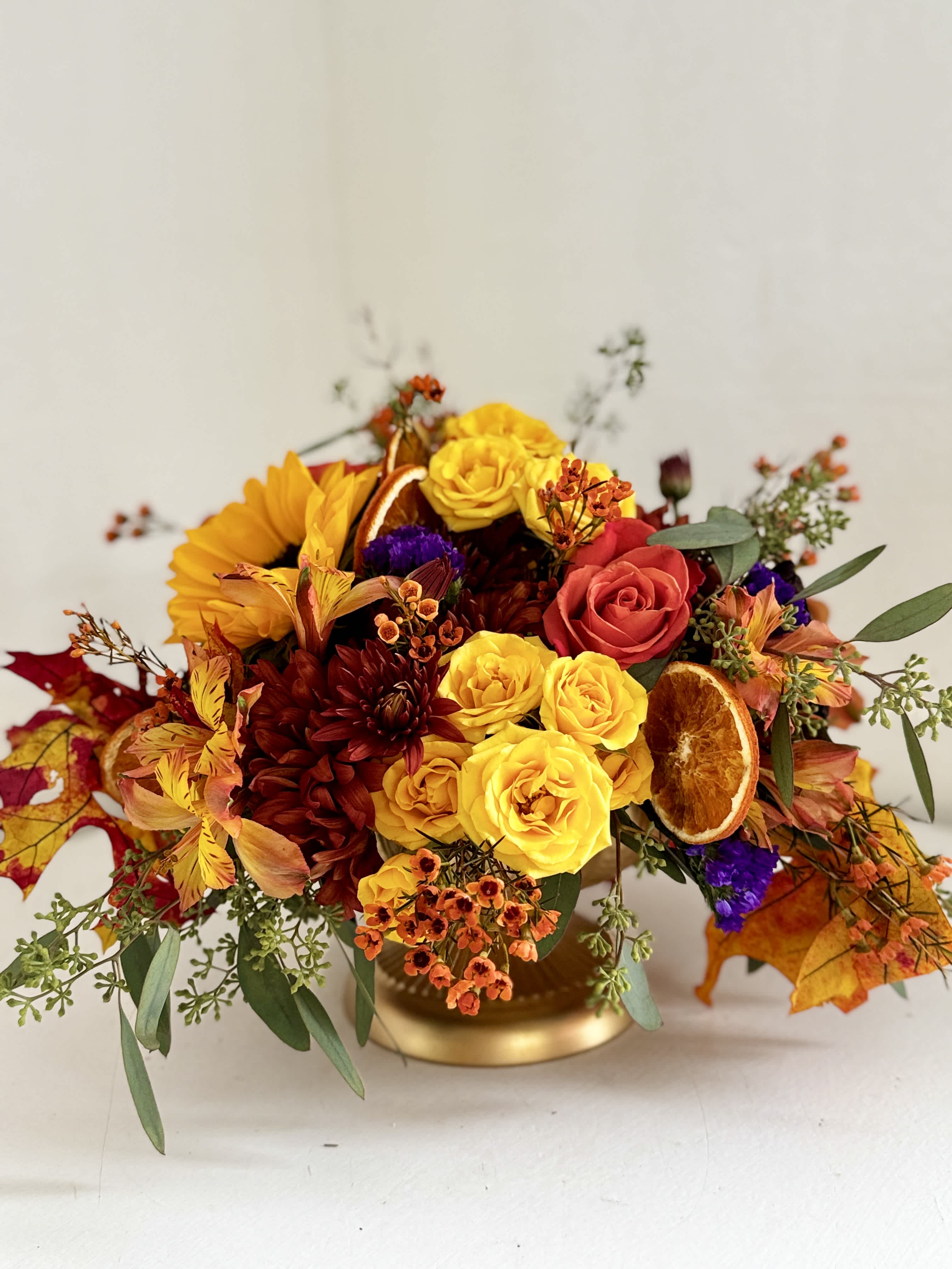 Autumn bouquet with yellow and red roses in a gold vase