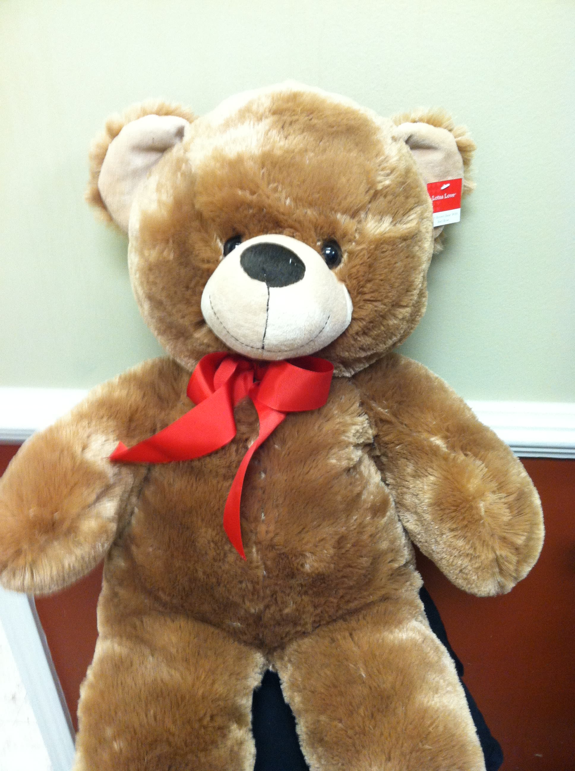 Large brown teddy bear with a red ribbon bow