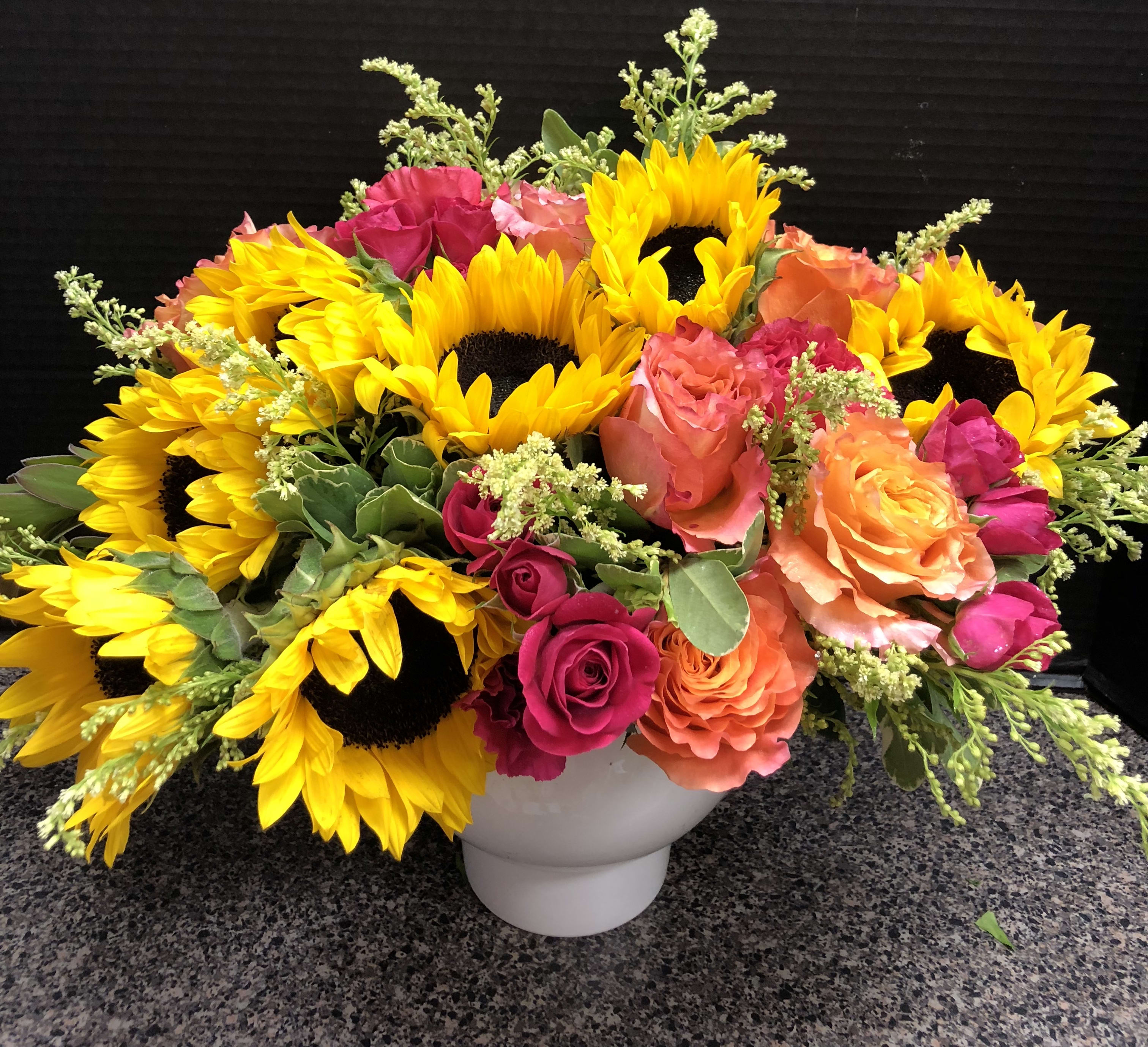 Bright sunflower and rose arrangement in a white vase