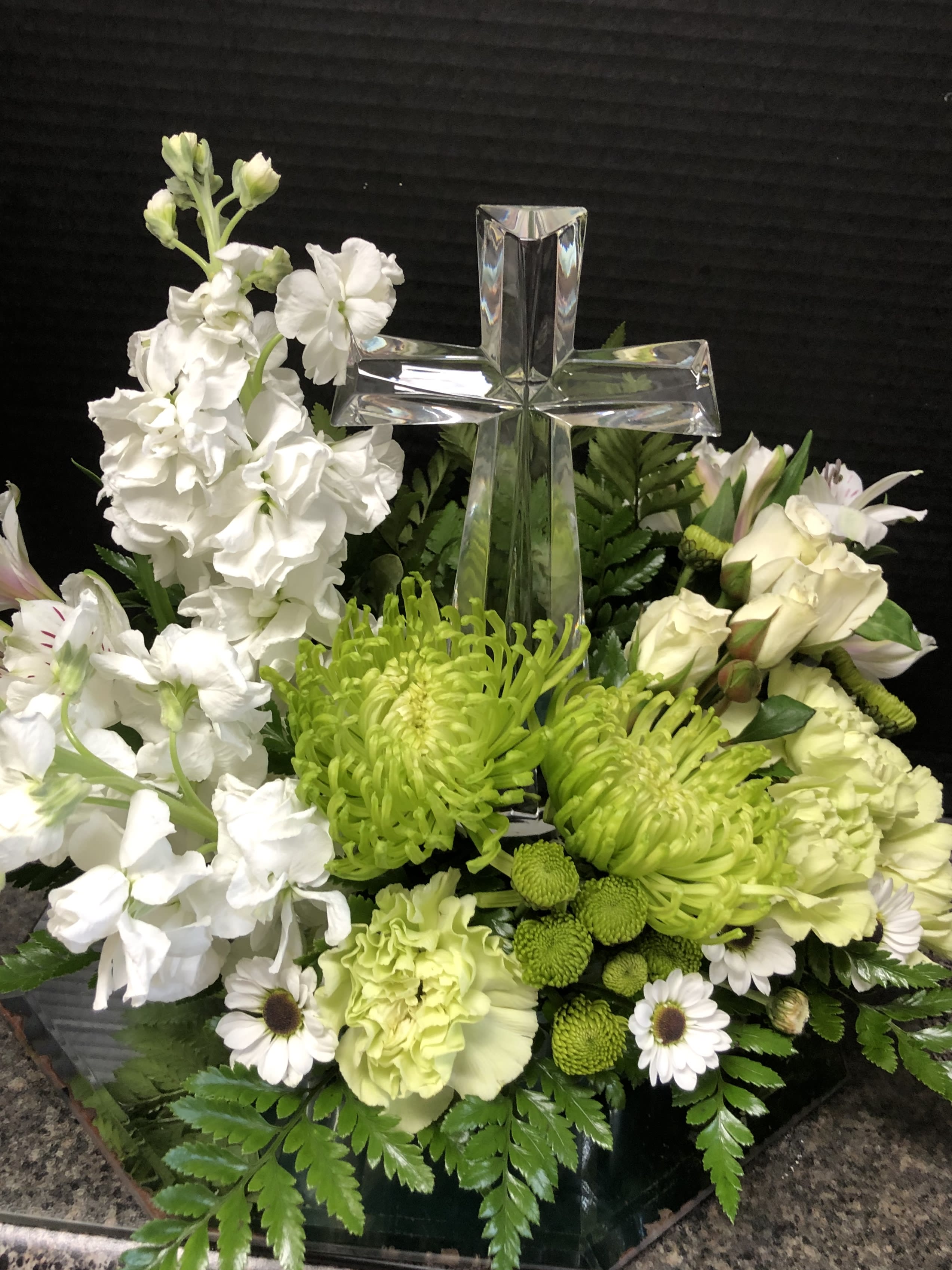 White and green floral arrangement with a clear glass cross centerpiece
