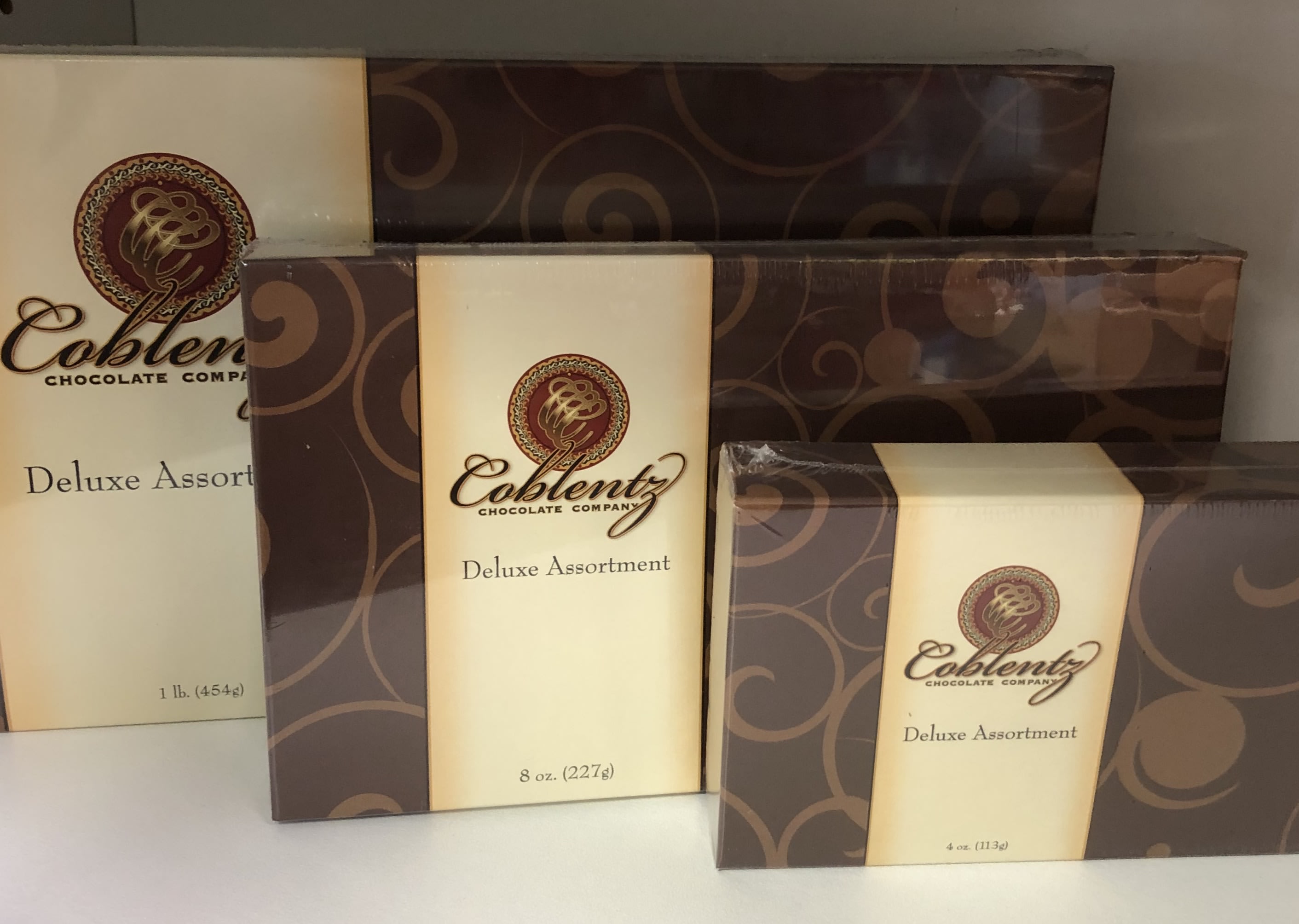 Three boxes of Coblentz Deluxe Assortment chocolates stacked together
