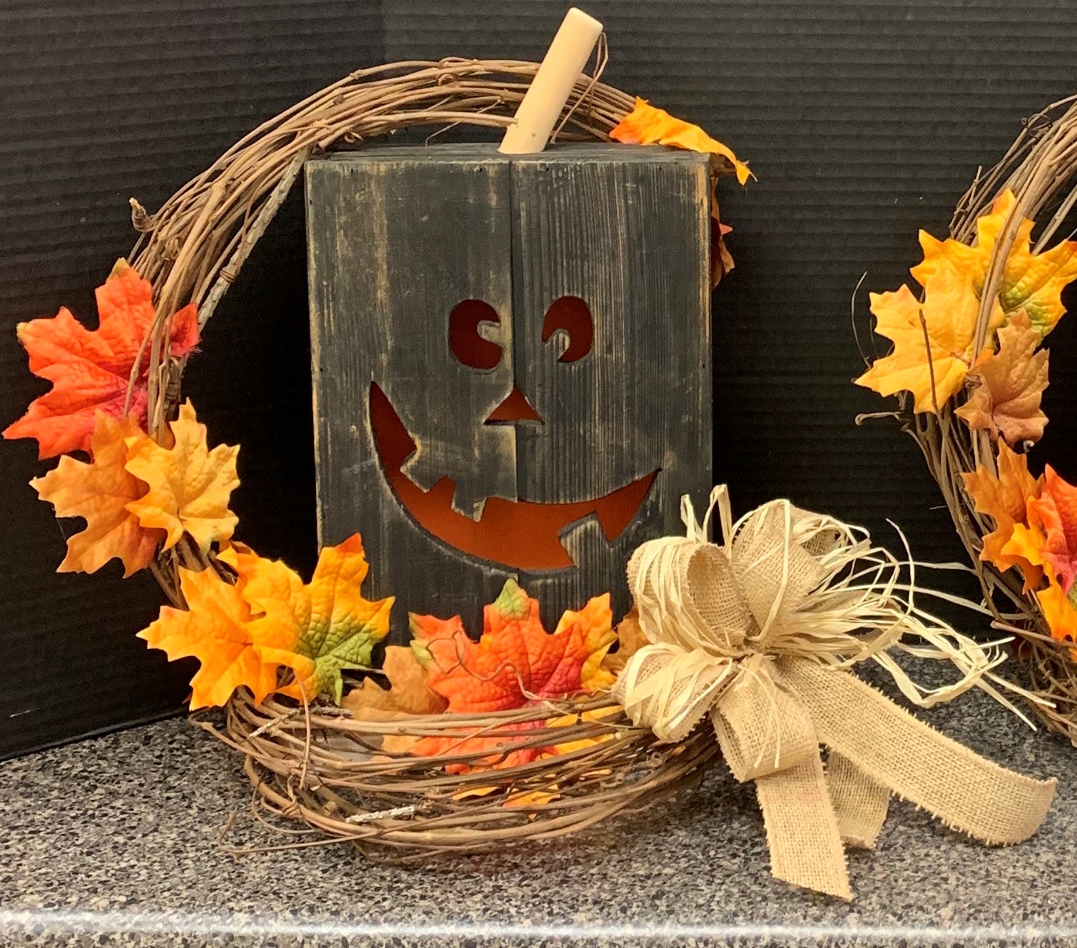 Halloween wreath with orange leaves and a jack-o'-lantern sign
