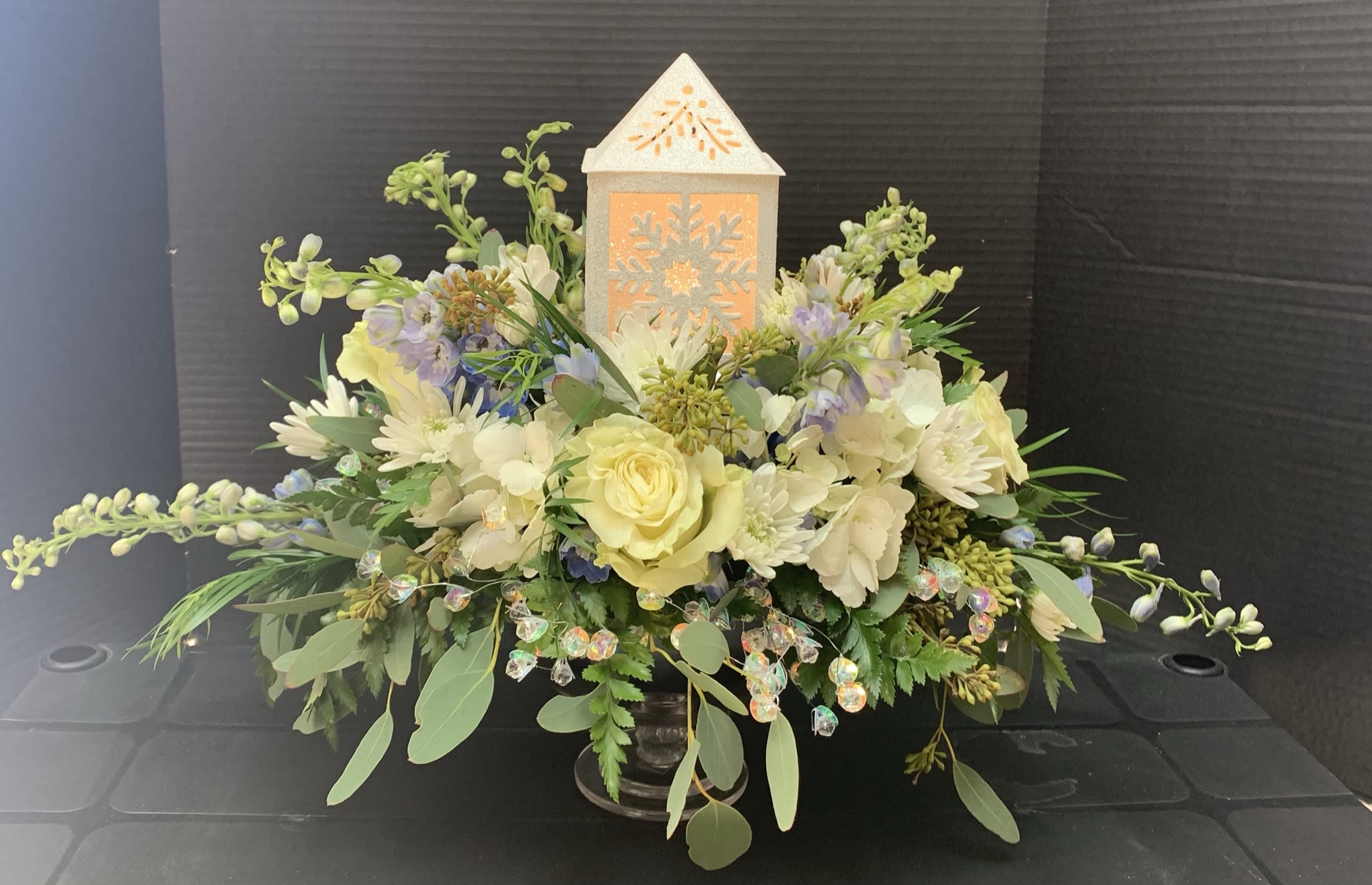 Cream and pale yellow floral arrangement with a lit lantern centerpiece