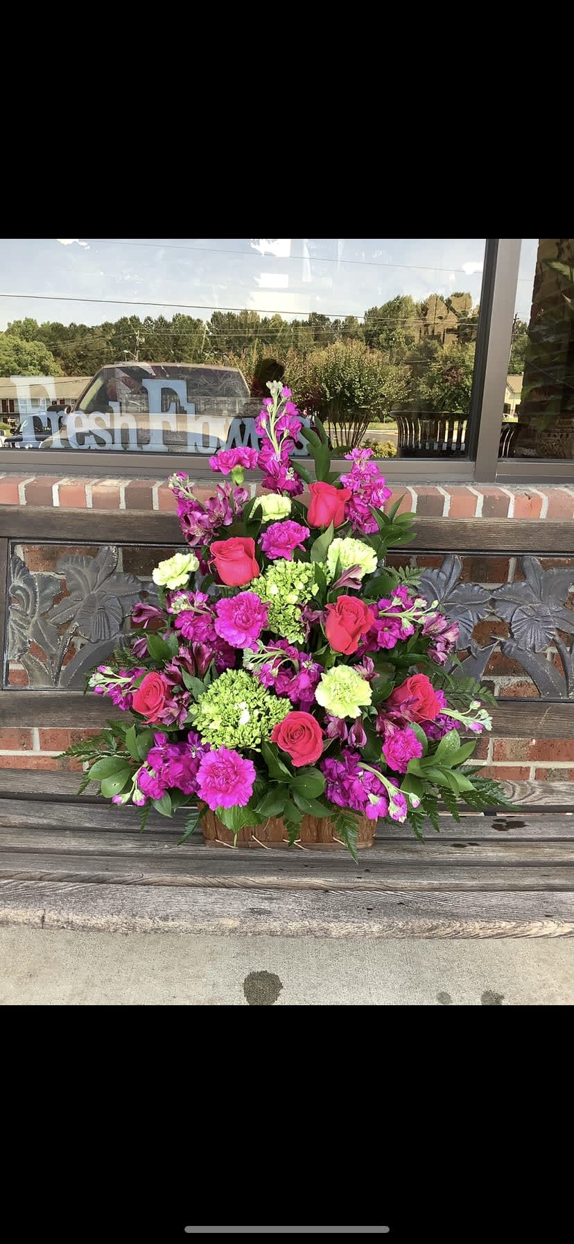 Pink and magenta floral arrangement in a wooden basket