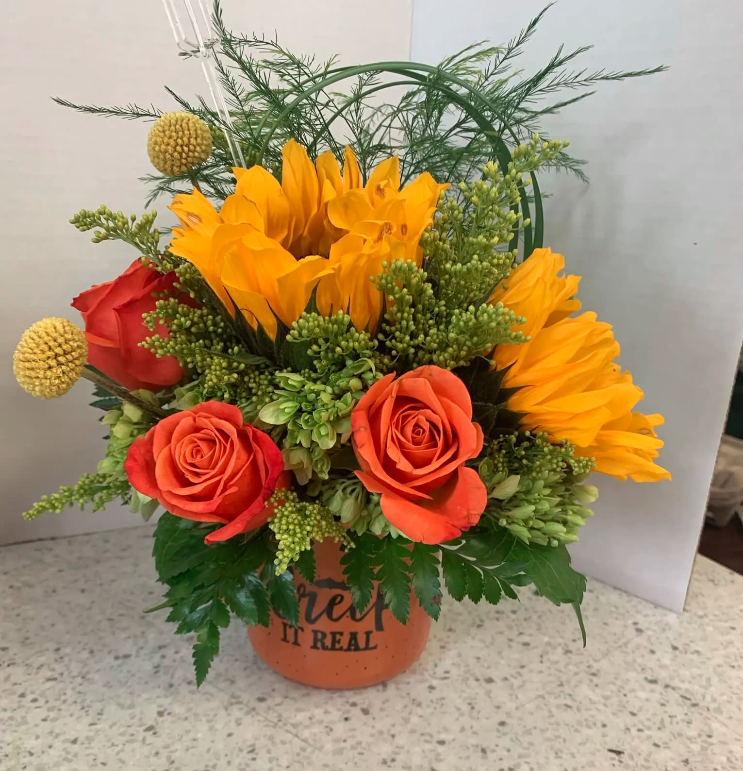 Orange and red roses with yellow blooms in a terracotta pot