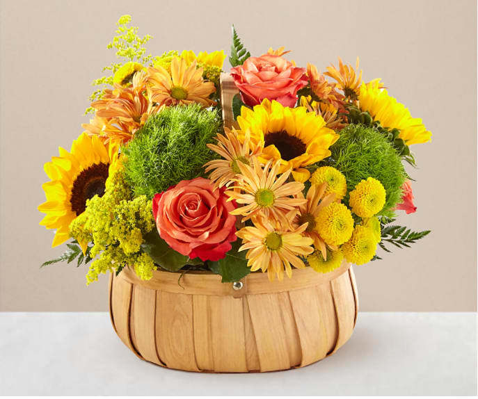Basket arrangement with sunflowers, roses, and yellow daisies