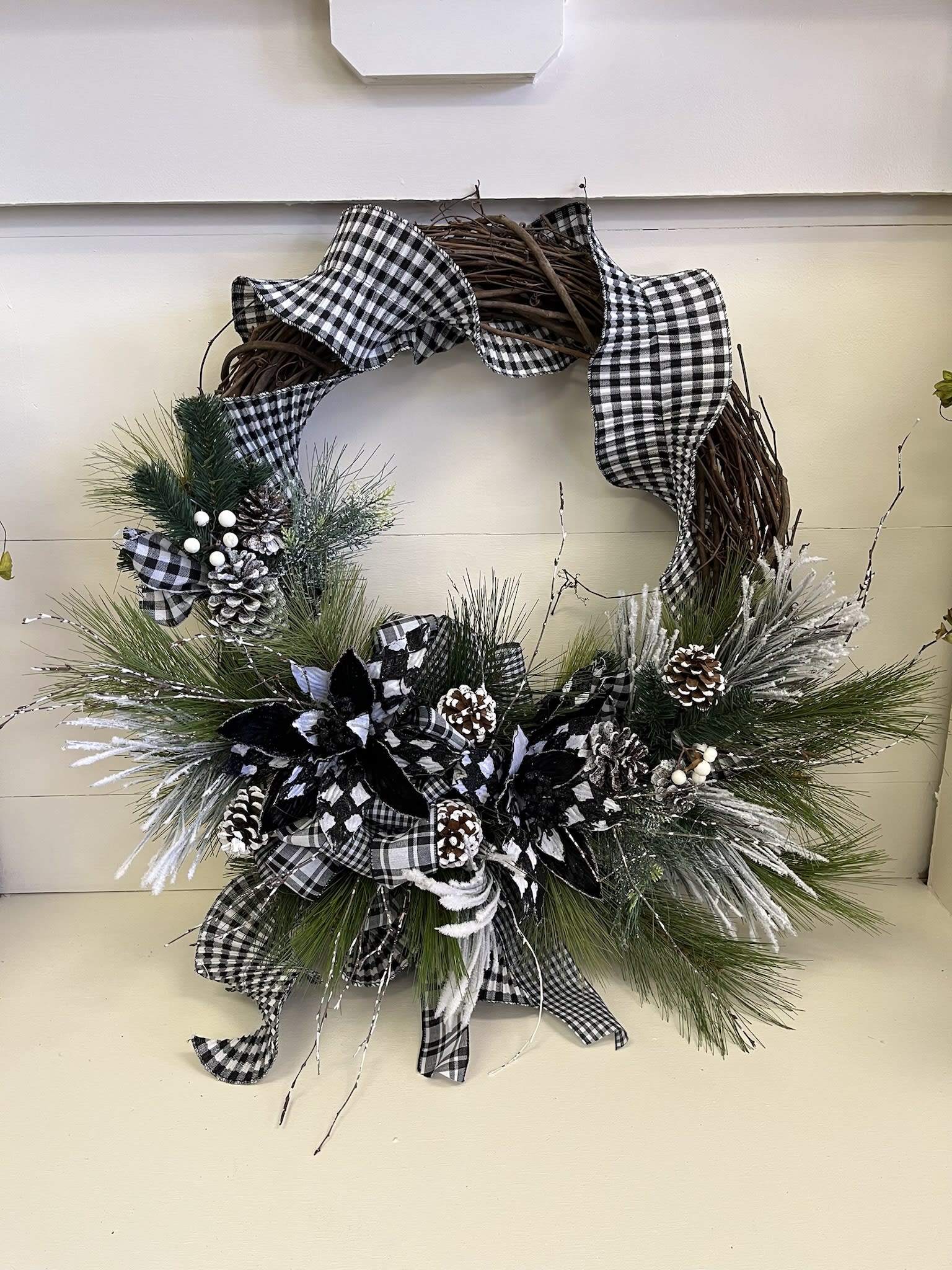 Black-and-white plaid wreath with pinecones and frosted greenery