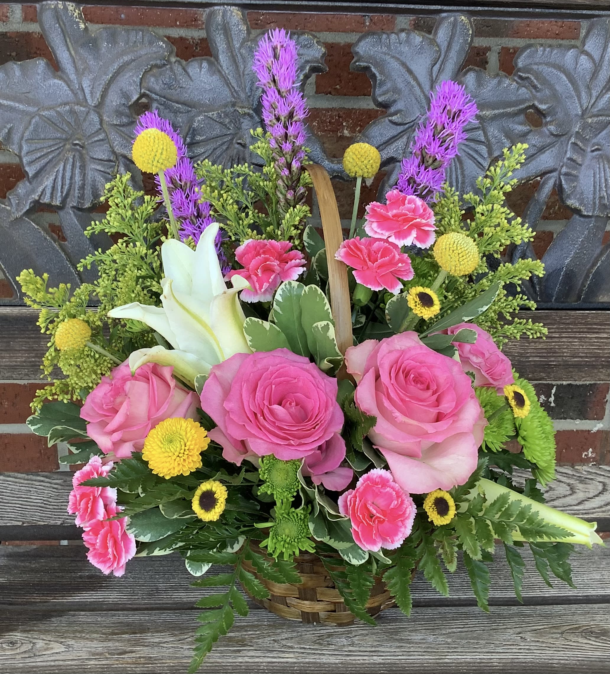 Basket arrangement with pink roses, white lilies, and yellow accents
