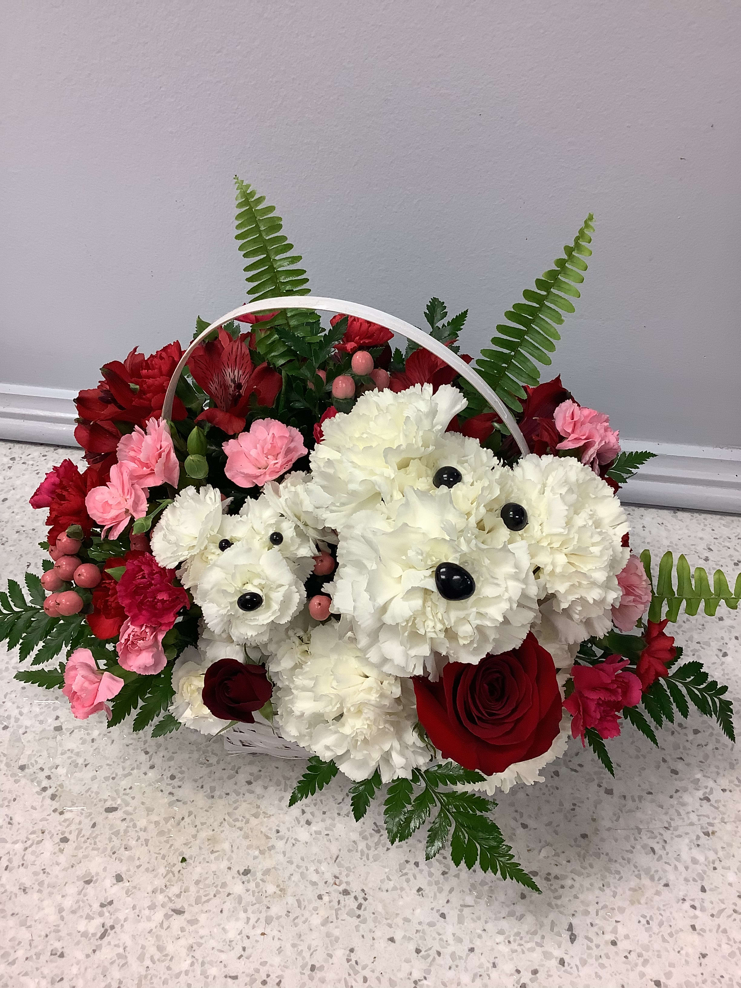Basket arrangement of red, pink, and white flowers with fern accents
