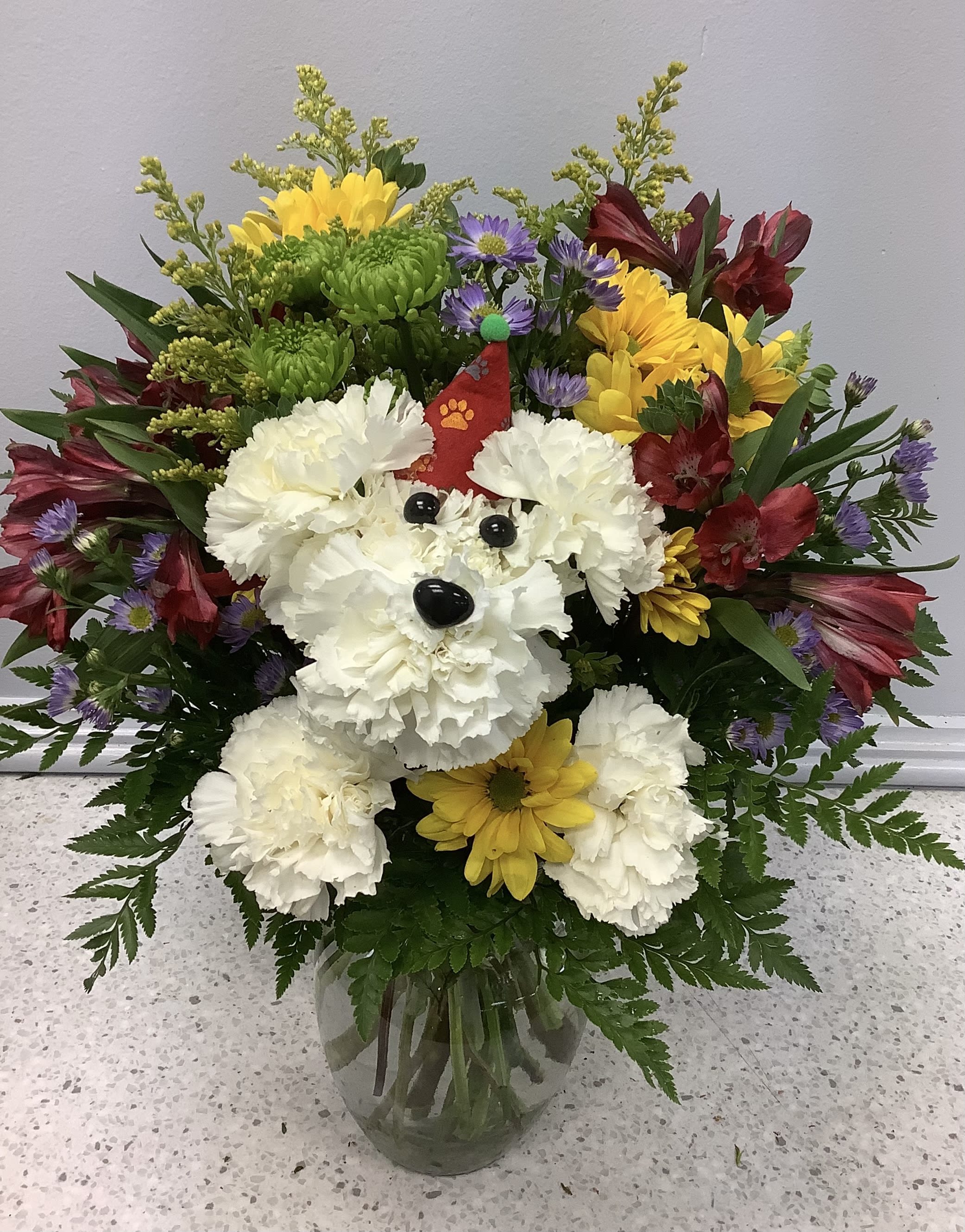 Colorful bouquet with a dog face made of white carnations in a glass vase