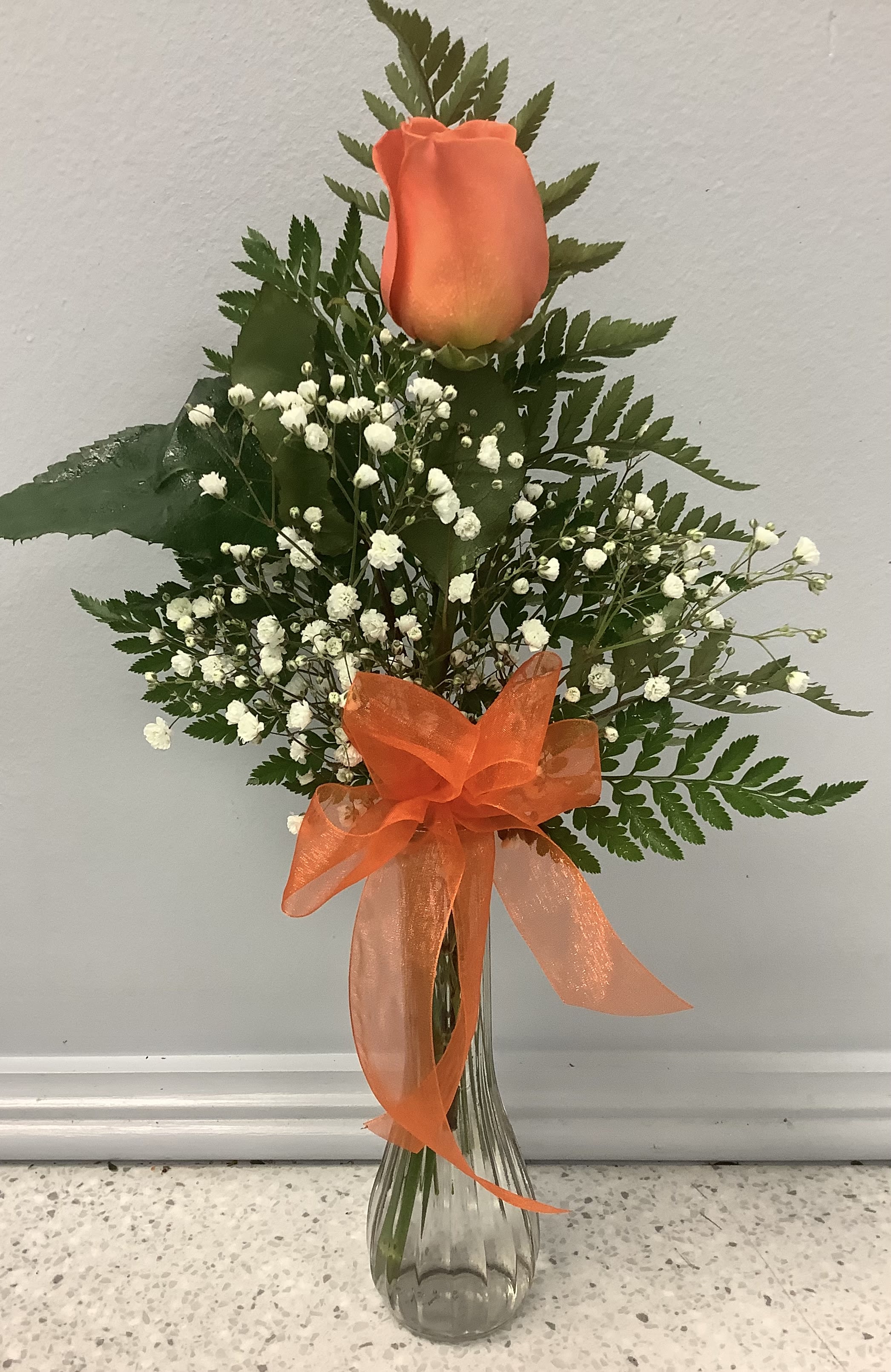 Orange rose arrangement with baby's breath in a glass vase and orange ribbon