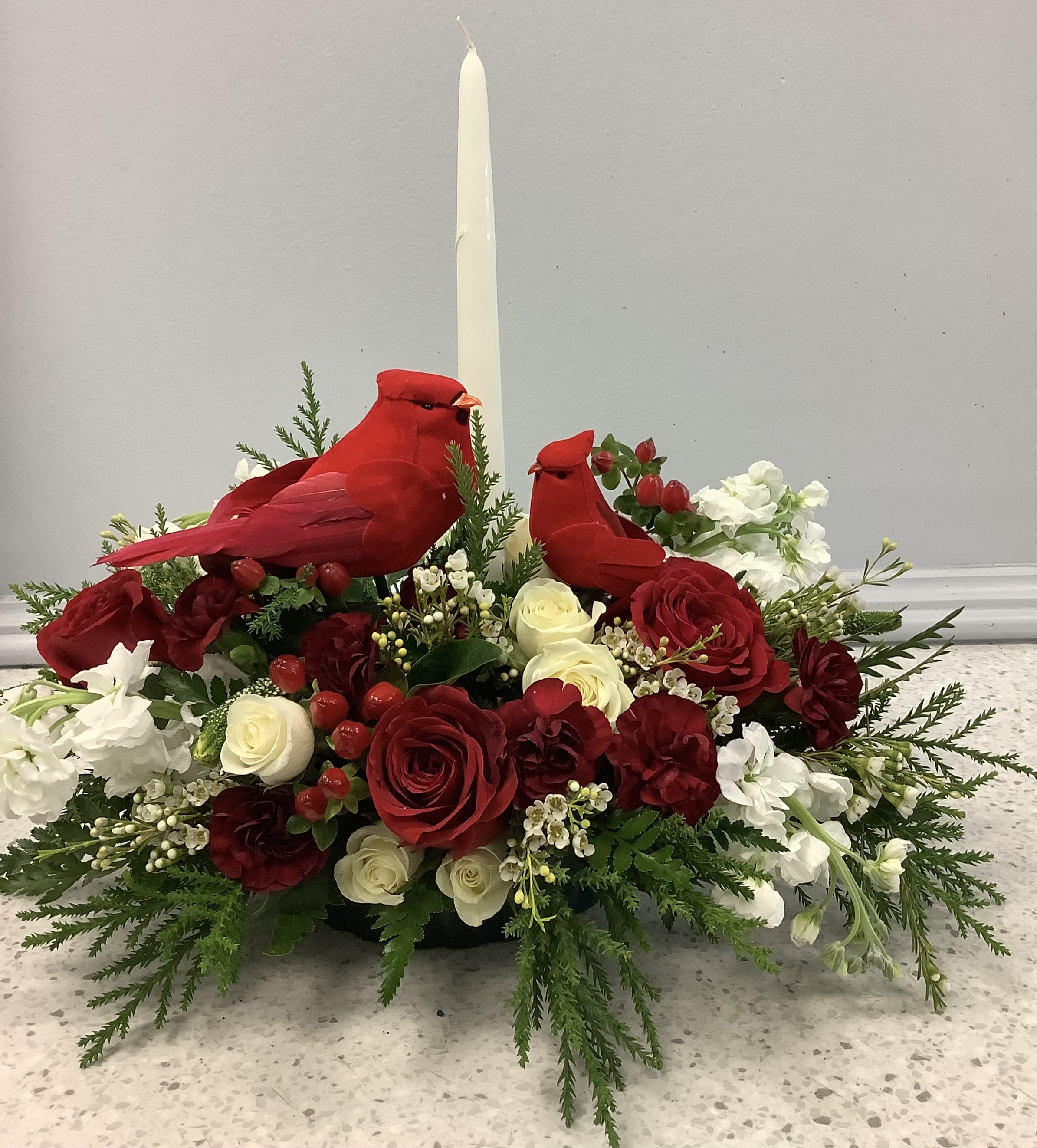 Red cardinal figurines in a floral centerpiece with a tall white candle