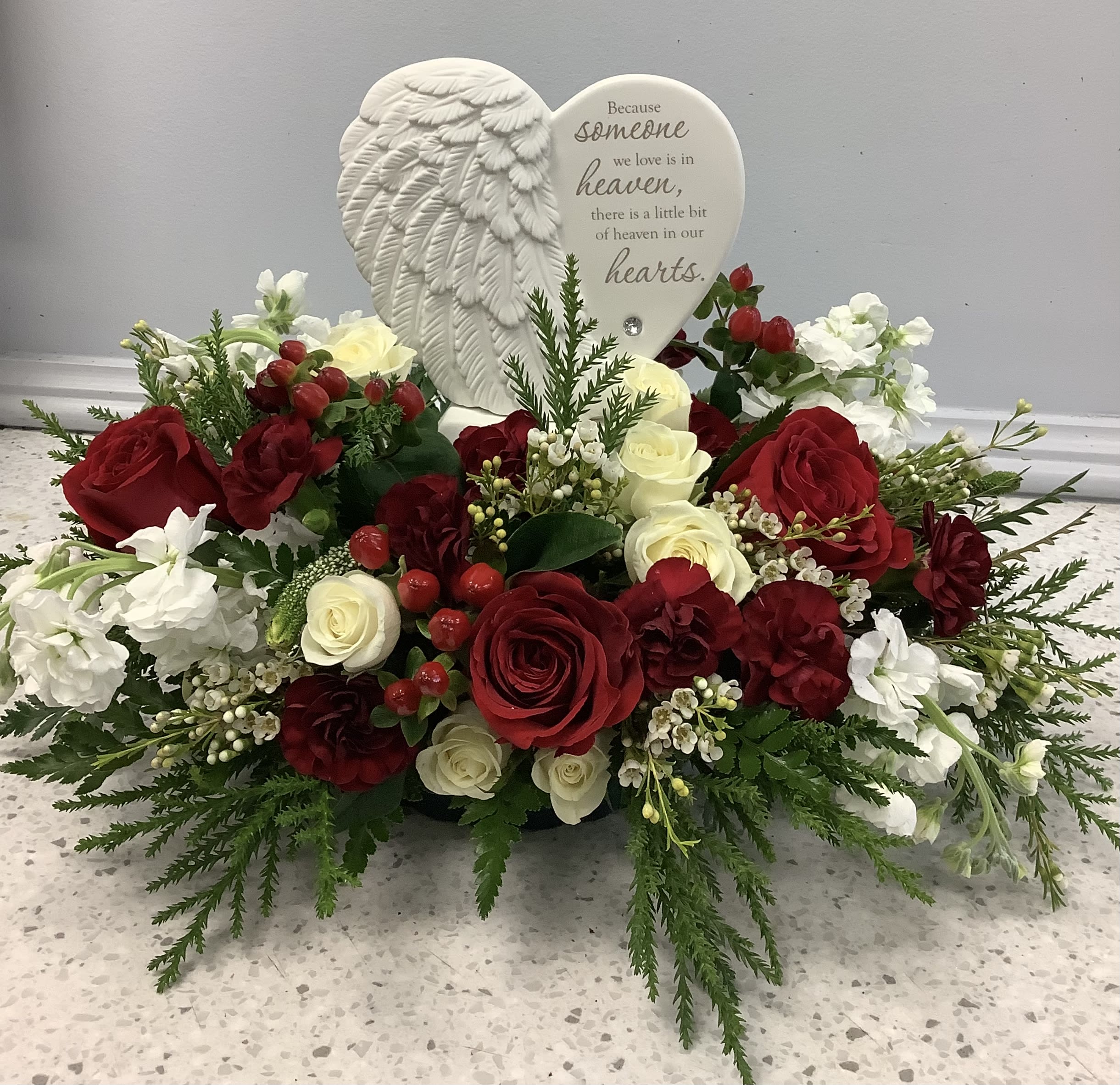 Heart-shaped sympathy arrangement with red and white roses and a memorial plaque