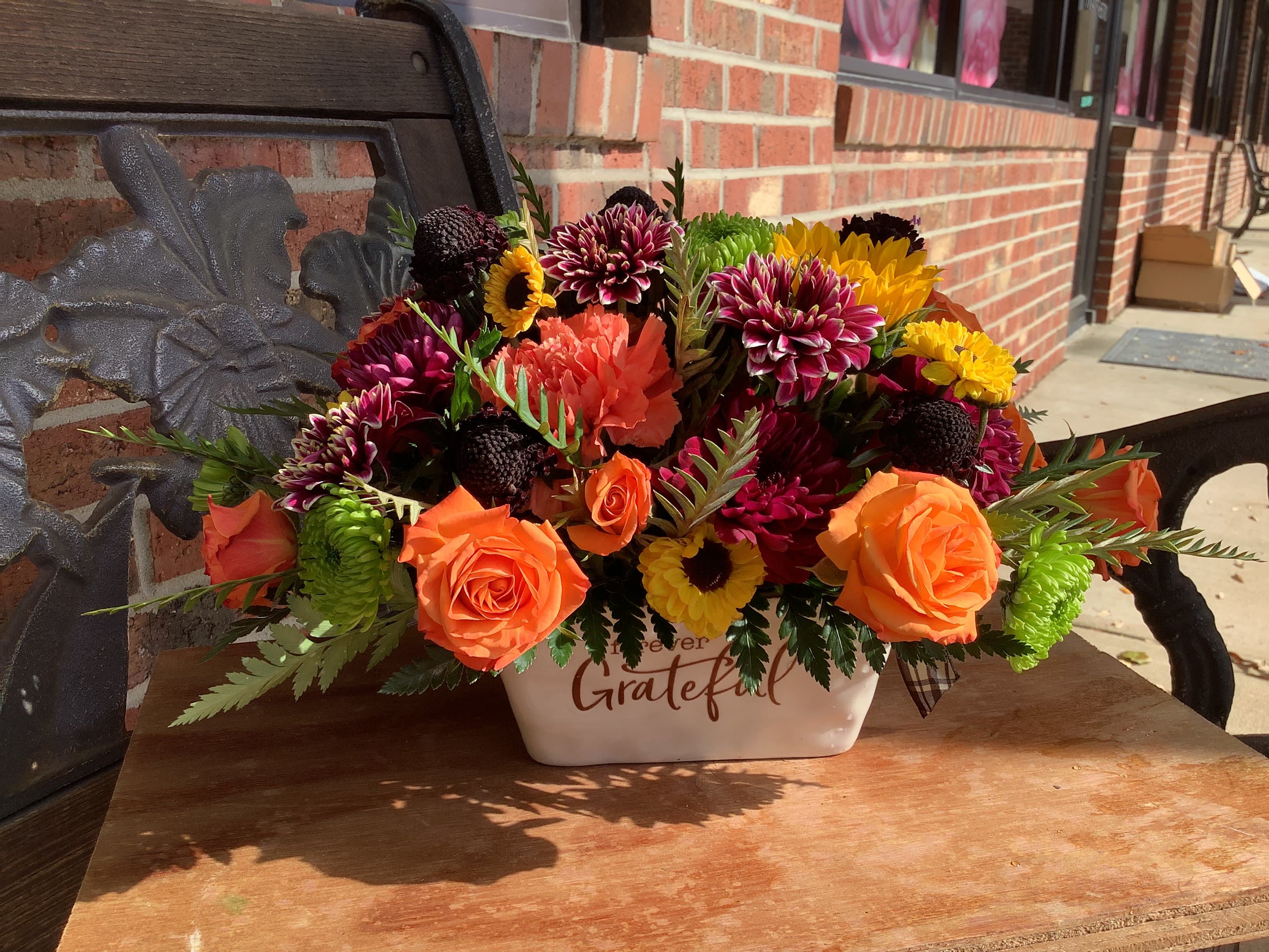 Orange roses and mixed mums in a white ceramic container