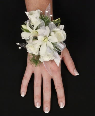 White floral wrist corsage with ribbon on a person's hand