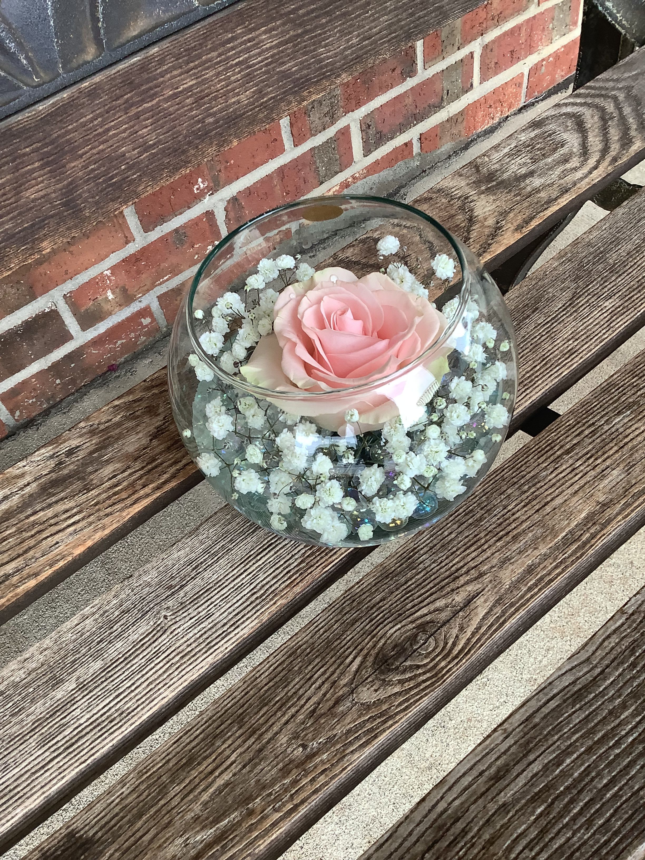 Pink rose in a clear glass bowl with white baby's breath