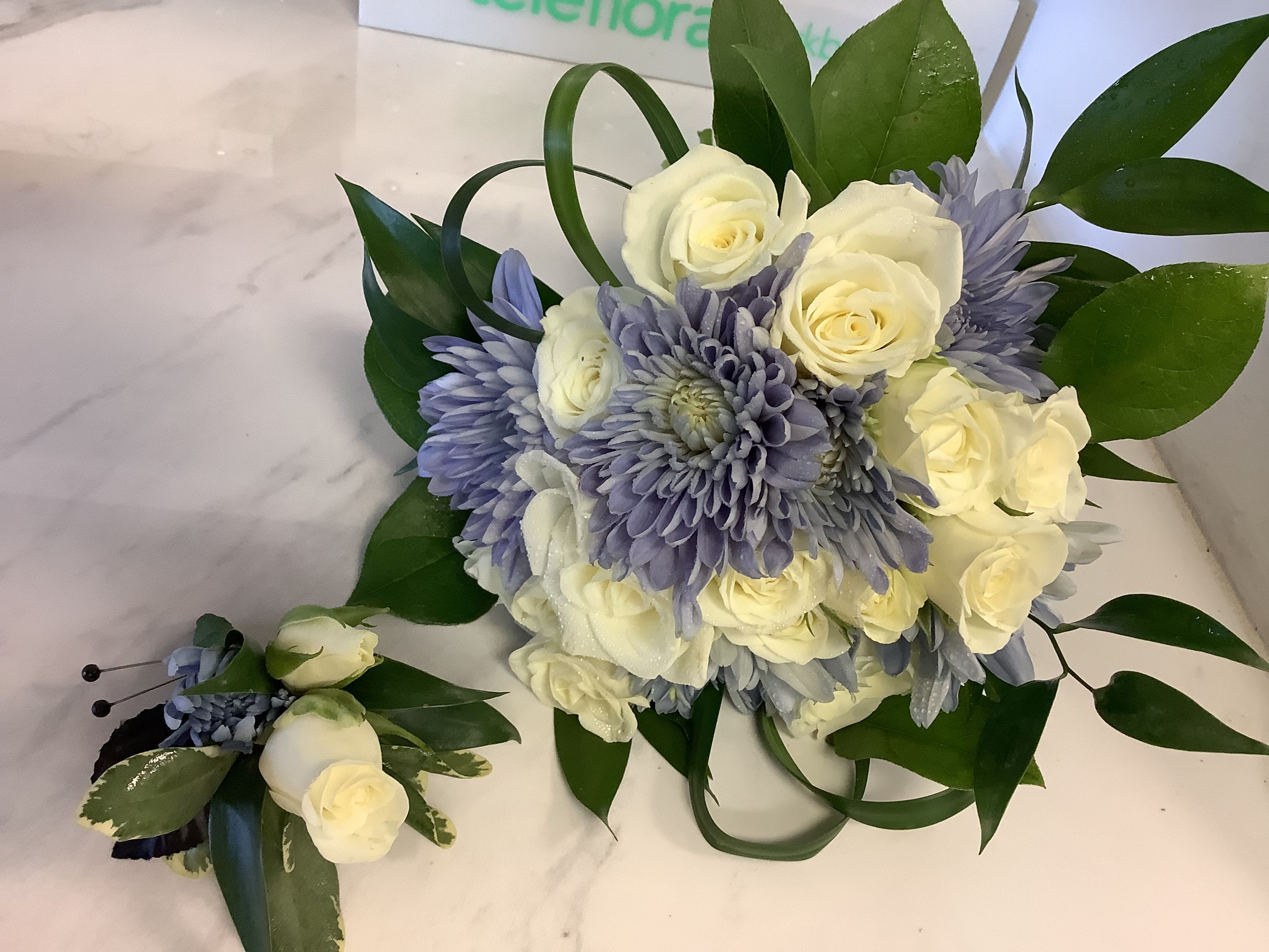 White roses and lavender chrysanthemums with greenery, plus a matching boutonniere