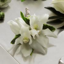 White orchid corsage with green accents on a light surface